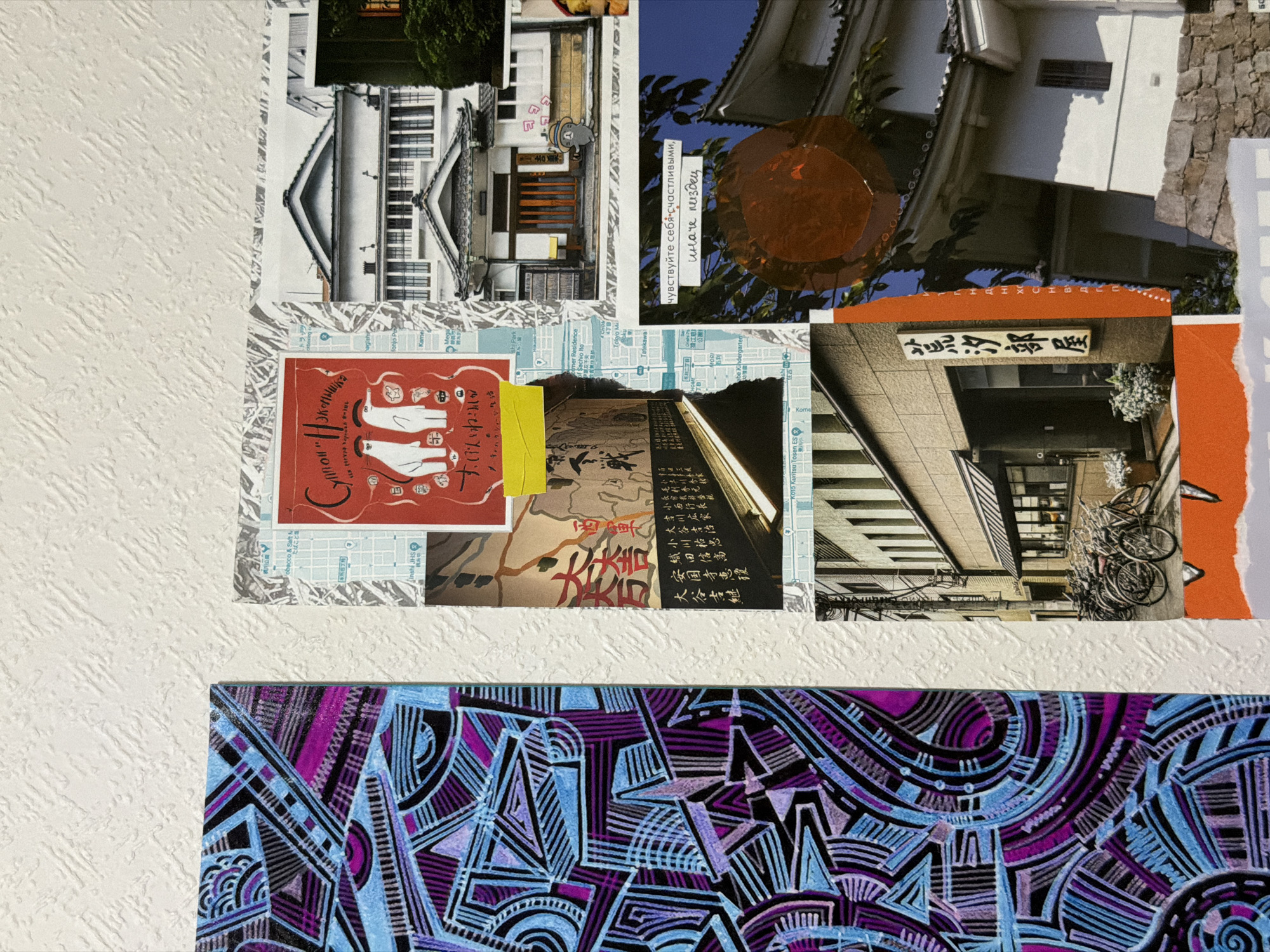 The image is a collage of various pictures and materials, mounted on a textured white wall. On the left is a vertical section of a colorful abstract artwork featuring geometric patterns in shades of purple, blue, and black. To the right of this artwork, there are several pasted elements. A red card with two white cartoonish figures and Japanese text is visible, along with a piece of a city map and a picture of traditional Japanese architecture. Below this, there is another collage element featuring a street scene with a building and bicycles, and further down, a vertically oriented Japanese sign. In the upper right portion of the collage, there's an image of a white Japanese building with a dark-tiled roof. In the lower right, a section of a stone wall is visible beneath the roofline of a white structure. A circular, reddish-brown element is pasted over a background of blue sky and foliage, with Russian text overlaid on it. There are no discernable people in the image, nor any specific landmarks that would indicate a location in Moscow, Russia. The scene is static and appears to be a collection of decorative elements.