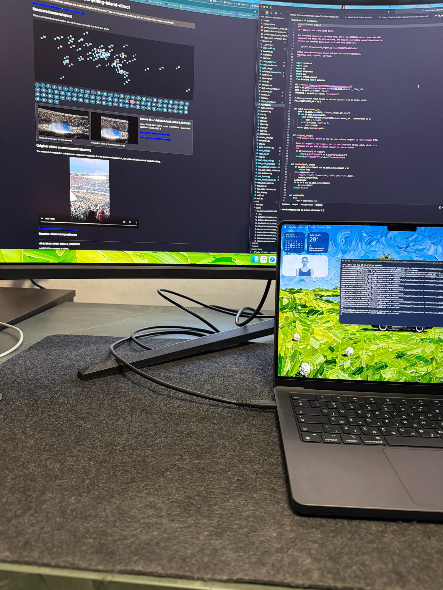 This image depicts a modern workspace setup with two computer monitors and a laptop, situated on a dark gray desk mat. The primary monitor, a large curved display, shows a complex interface with a scatter plot of blue and orange dots, a grid of numbered circles, and two smaller image previews. Below these elements, there is a video player with the timecode "0:00 / 0:05" and text indicating "Source-view comparisons." The right side of the large monitor displays code with syntax highlighting.

The secondary display, a laptop screen, shows a vibrant green and yellow wallpaper depicting rolling hills with scattered white objects, possibly decorative elements or stylized coins. A calendar widget displays "Tue Aug 18" with the temperature at "29°" and the city of "Kafr Yasif" with the text "Becoming for high temperatures." Below the wallpaper, there is a terminal window displaying command-line text, including file paths and dates.

The scene is focused on technology and digital work, with cables from the monitors and laptop visible. The overall environment suggests a home office or a professional setting dedicated to software development or data analysis. The presence of the city name "Kafr Yasif, Israel" on the laptop screen, combined with the technology, implies this workspace is located within or associated with that region. There are no visible people in the image.