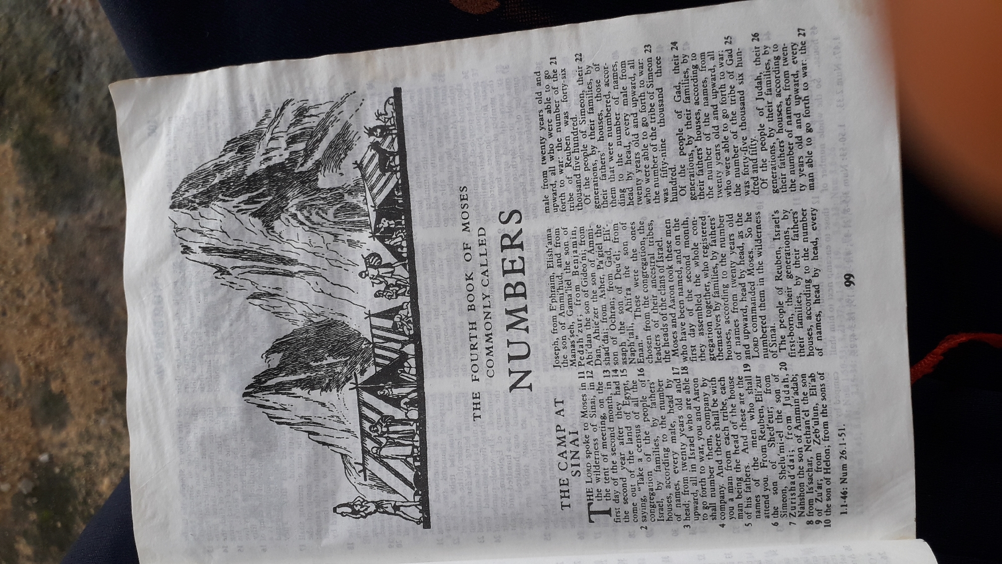 The image shows a page from a book, likely a Bible, with a black and white illustration at the top depicting a mountainous landscape with tents and figures of people and animals. Below the illustration, the text reads "THE FOURTH BOOK OF MOSES COMMONLY CALLED NUMBERS". The main body of the page contains text arranged in columns, detailing names, genealogies, and census information. The page is partially opened, with a red thread visible at the bottom right, suggesting it is a bound book. The surrounding area is blurred and appears to be a floor or surface. There is no information within the image that indicates a location in Nkpor, Nigeria.