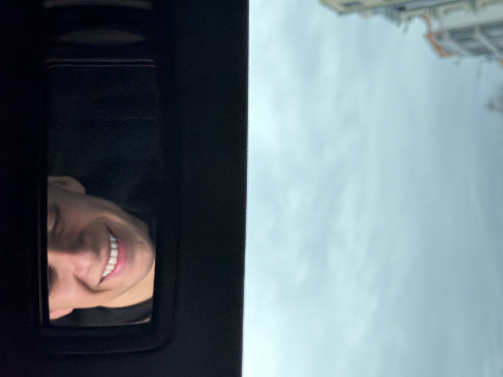 A person is peering through the open sunroof of a vehicle. The sky and the top of a building are visible outside the vehicle. This is likely a scene in Plovdiv, Bulgaria.