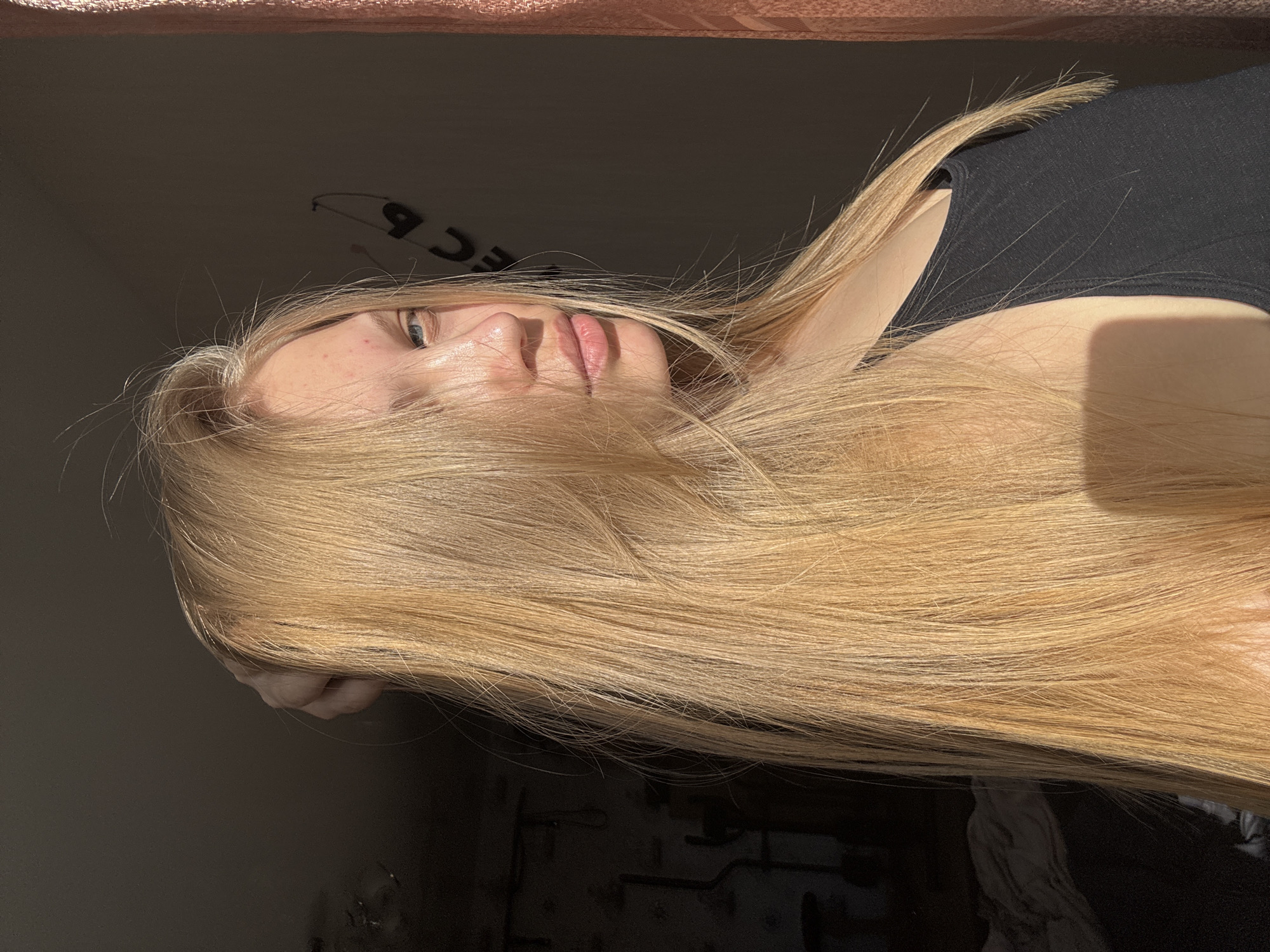 A woman with blonde hair is lying down. The background is dimly lit, and she is wearing a black tank top. It is not possible to determine the location with certainty, but the image includes a reference to the city of Chaikovsky, Russia.