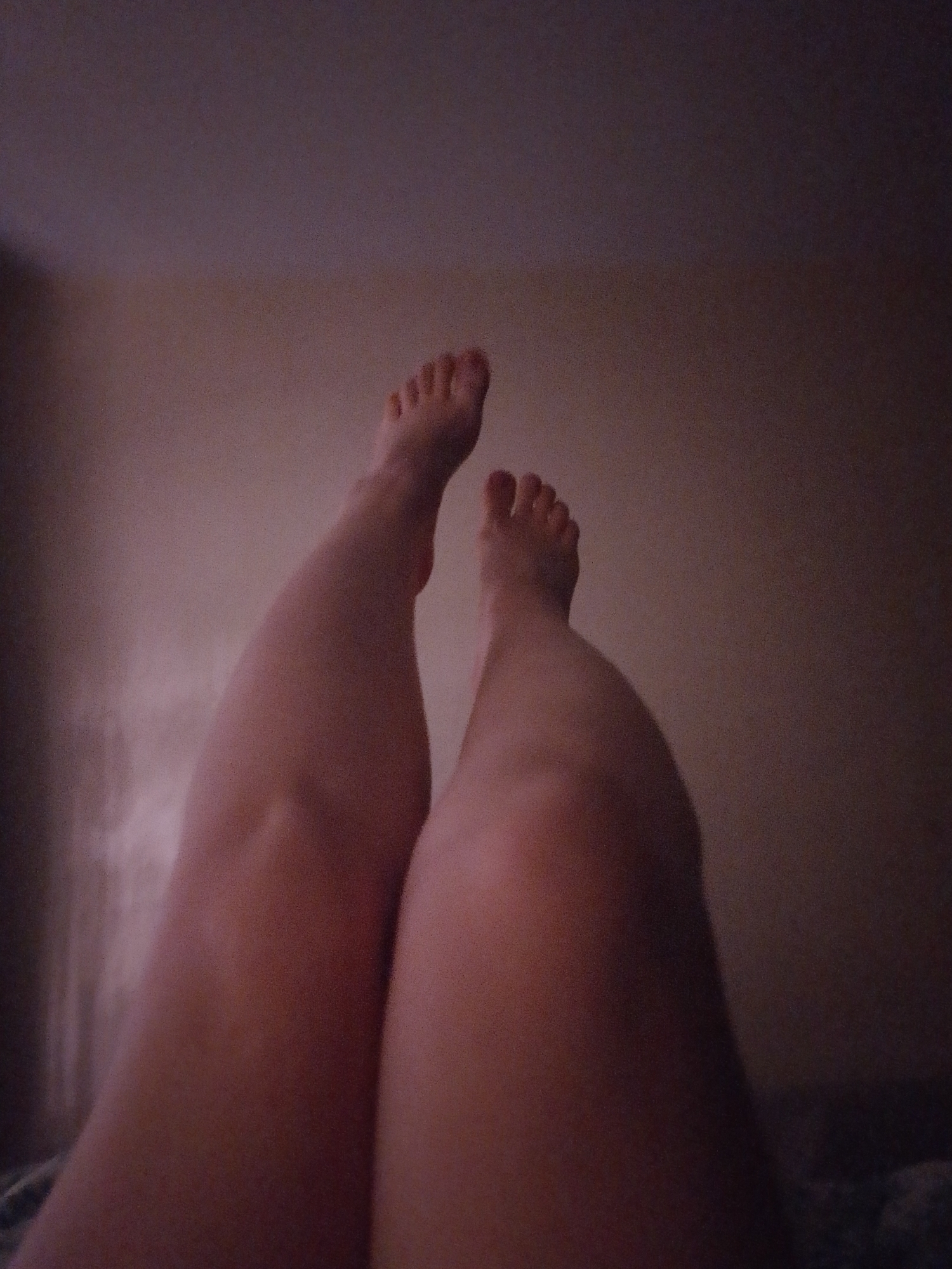 The image shows a pair of legs and feet, presumably lying on a bed or other surface. The background is a plain wall. There is no indication of location in Izhevsk, Russia or any other city.
