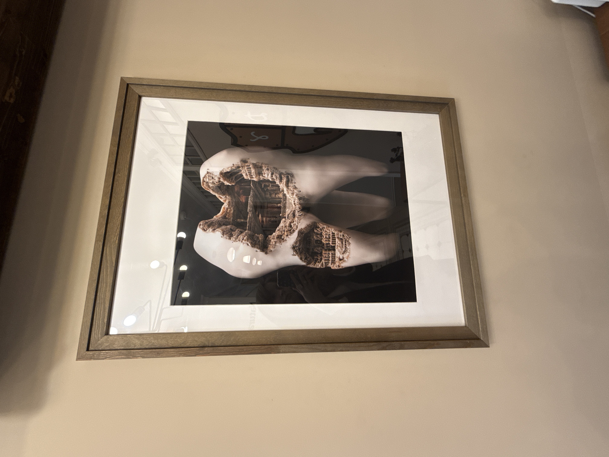A framed picture hangs on a light beige wall. The picture depicts a stylized tooth with the interior represented as the ruins of a building. The location is not identifiable as Izhevsk, Russia.