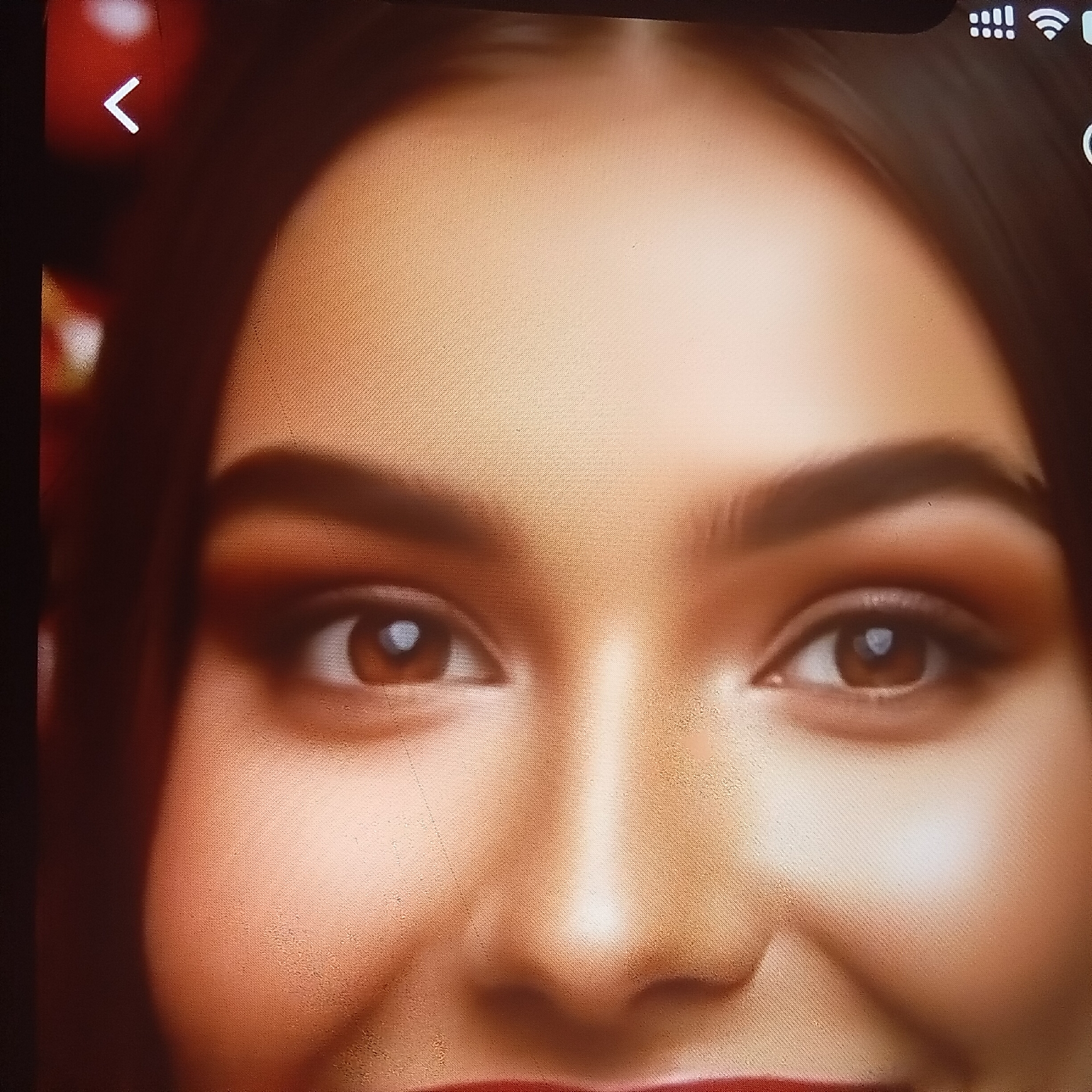 The media file is a close-up, portrait-style image focusing on a person's eyes, nose, and mouth. The subject appears to be a young woman with brown eyes and well-defined eyebrows, accentuated by makeup. The lighting suggests an indoor setting, possibly a studio, with warm tones and soft illumination that highlights the contours of her face. The background is dark and blurred, keeping the focus entirely on the subject's features. There are no clear indications of the time of day, weather, or specific location cues within Almaty, Kazakhstan. The overall mood conveyed is one of subtle beauty and poise. The visible text in the image consists of icons at the top right corner, likely representing battery life, signal strength, and Wi-Fi connection, suggesting the image is being displayed on a digital device.