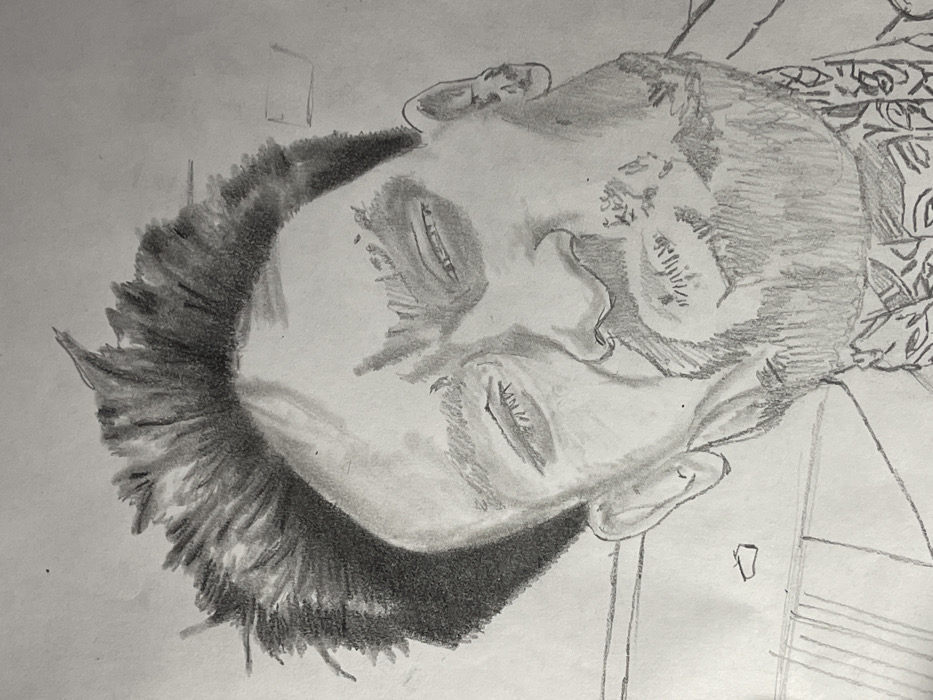 The image is a pencil drawing on light-colored paper, depicting a close-up portrait of an adult male. The subject's head and upper neck are prominently featured, angled upwards towards the viewer. The male has dark, textured hair styled with volume on top, and a full beard and mustache rendered with varied pencil strokes. His eyes are partially closed, with visible eyelashes, and distinct shading indicates contours around the eyes. His mouth is pursed, creating a distinct facial expression. A patterned design, possibly a tattoo or fabric print, is visible on the lower neck and extends towards the bottom of the frame, characterized by abstract, interlocking shapes. The background is plain and light-toned, with faint sketch lines visible on the paper, indicating the drawing medium. No active interactions or specific environmental details beyond the drawing surface are discernible. This image is associated with the city of Jos, Nigeria.