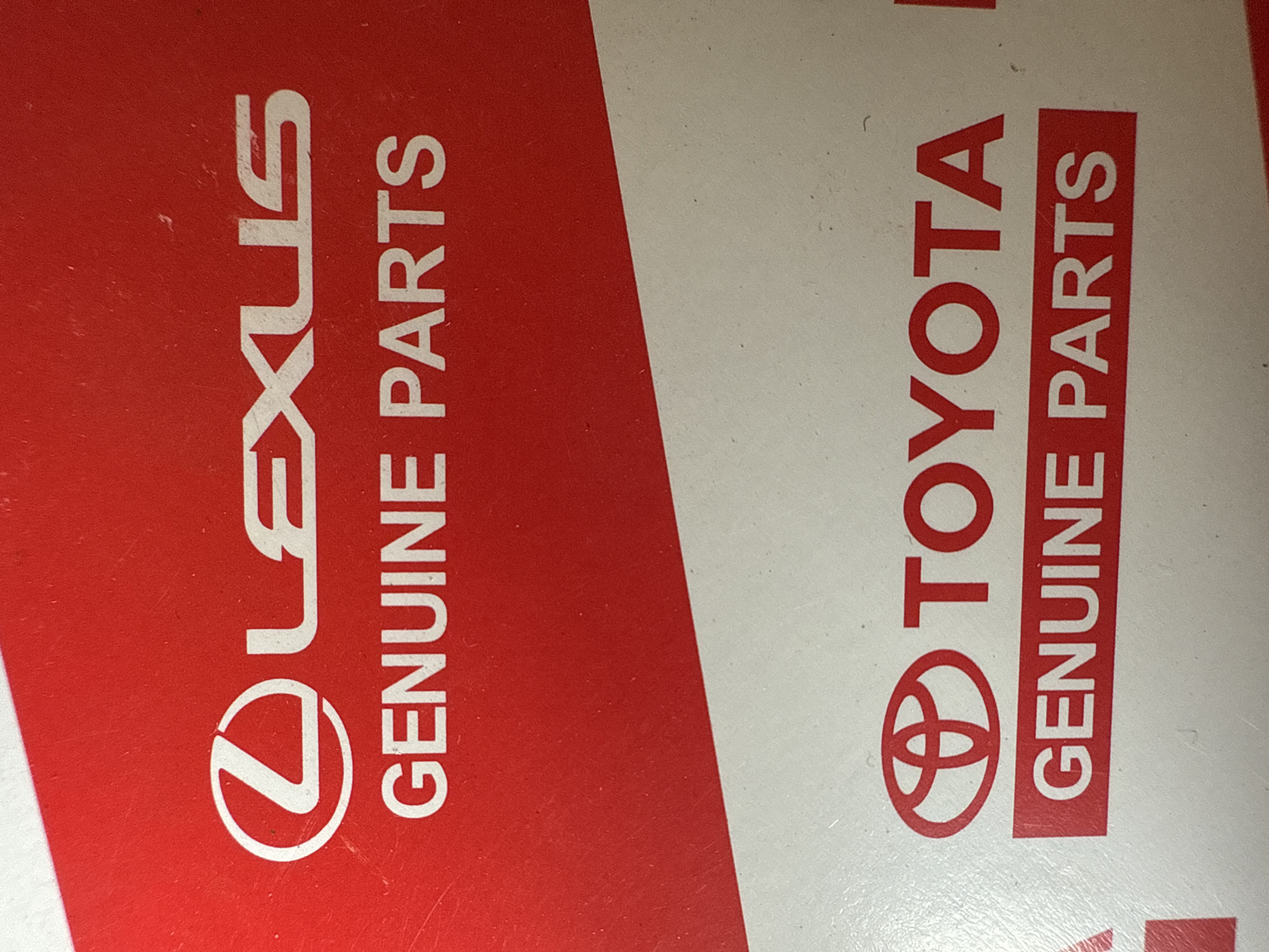 The image shows the logos for Lexus and Toyota genuine parts. The Lexus logo and "GENUINE PARTS" are in white on a red background. The Toyota logo and "GENUINE PARTS" are in red on a white background. The location is Unknown, Unknown.