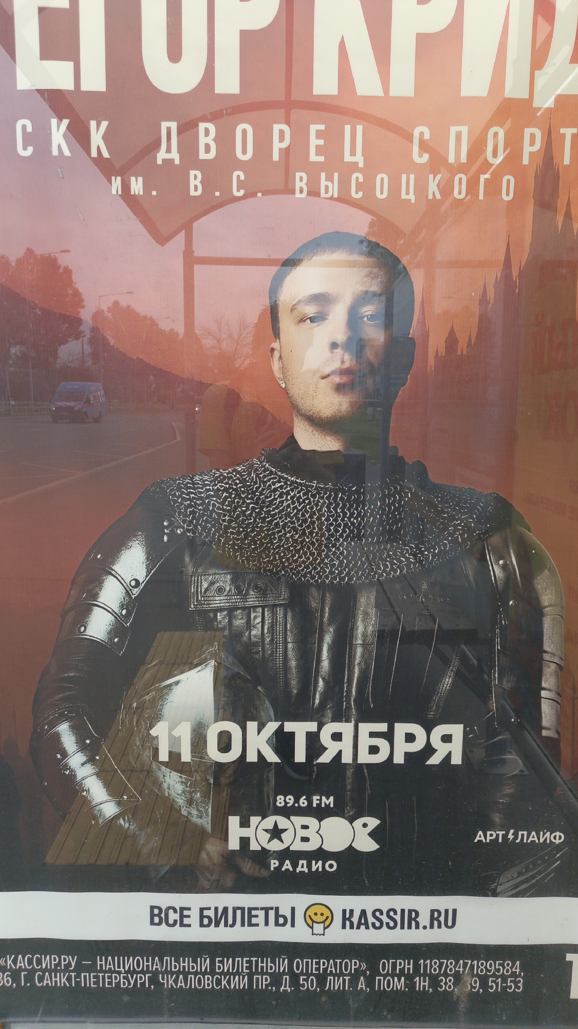 The image is a poster for an event. The poster features a man in a knight's outfit, holding a helmet. The text on the poster indicates the event is taking place on October 11th at the SKK Palace of Sports named after V.C. Vysotsky. The poster also advertises "New Radio" and "Kassir.ru" as ticket vendors. The background of the poster appears to be a blend of an urban landscape and a more stylized, possibly castle-like, architectural element. There are no visible elements within the image that directly indicate a location in Samara, Russia, though the content suggests an event in a city venue.