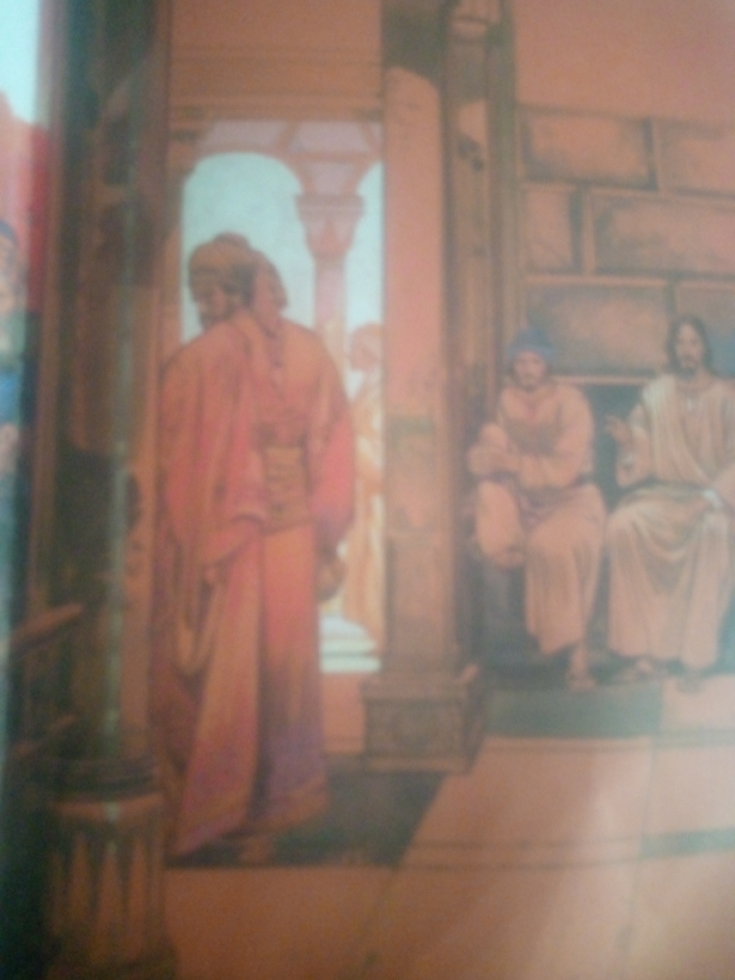 The image depicts a painting, rendered in a soft, diffused style, of a religious scene. In the foreground, a figure in a flowing, reddish-pink robe stands with their back to the viewer, facing an arched doorway. This figure appears to be interacting with another person whose form is less distinct. To the right, two figures are seated. One, on the left, wears a blue head covering and a light-colored robe, with arms crossed. The figure to their right is seated and wears a white robe, with one hand raised as if speaking. The background suggests an architectural setting with stone-like textures and columns. The painting is heavily blurred, making precise identification of details challenging. The location in the city of Jauro Yinu, Nigeria, is not visually represented or suggested by the content of the painting.