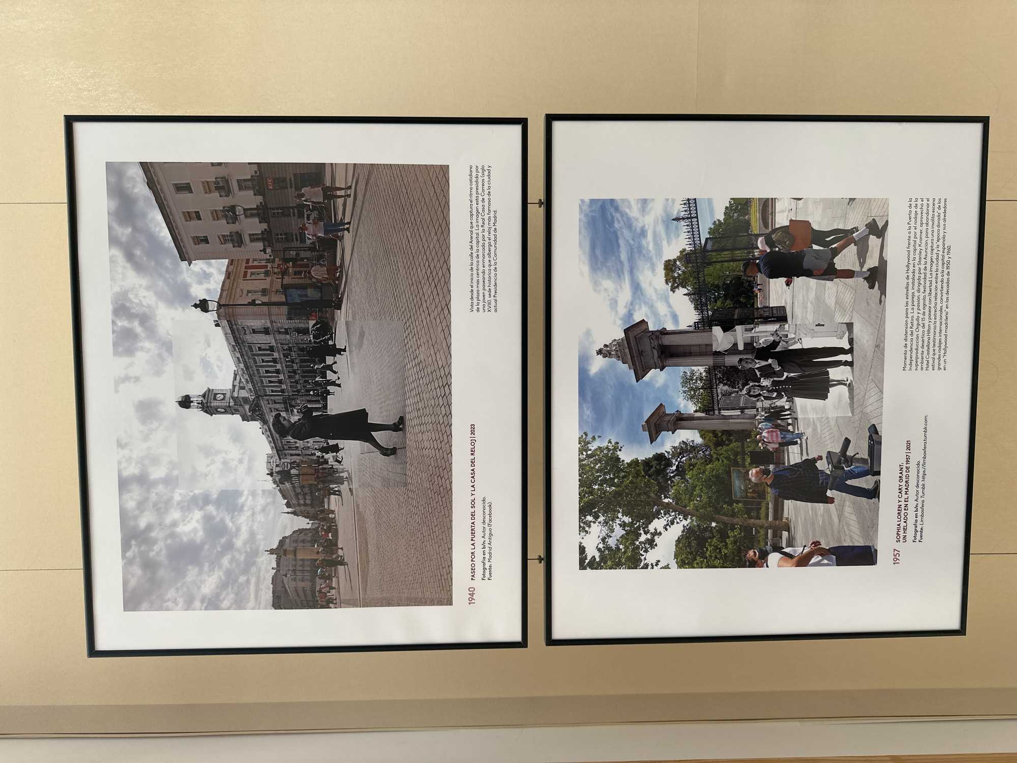 The image displays two framed photographs hanging on a light-colored wall. The upper photograph, dated 1940, is a black and white collage depicting a street scene in Madrid, Spain, specifically Paseo de la Puerta del Sol y la Casa del Reloj. A lone woman in a dark coat stands in the foreground, facing away from the camera, with a street crowded with pedestrians and buildings in the background. The lower photograph, dated 1957, is a color collage showing a scene in Madrid, Spain, featuring stars Sophia Loren and Cary Grant at the Puerta de la Independencia. Several people are visible in the frame, some wearing masks, suggesting a contemporary element to the collage. The background features a large entrance with ornate pillars and trees. Text below each photograph provides details about the image, including dates, titles, and sources.