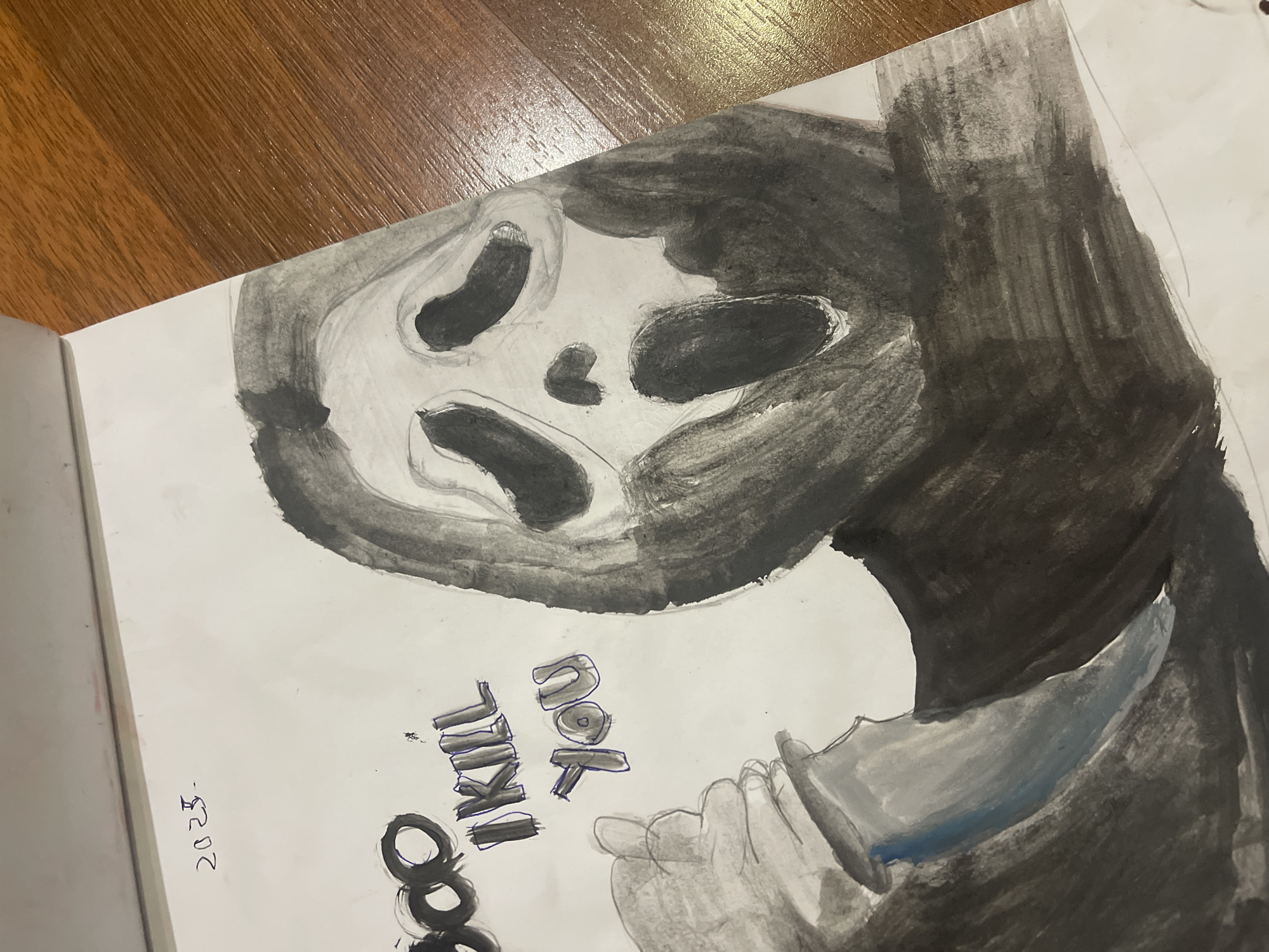 The image is a close-up, high-angle shot of a drawing on a white surface, possibly paper or a notebook, lying on a wooden table. The drawing depicts a stylized, ghostly figure with a Scream-like mask, rendered in black and gray ink or watercolor. The figure has large, dark eye and mouth openings. To the left of the figure, the words "BOO I KILL YOU" are written in black and blue ink. Below the text is a drawing of a hand holding a knife, with a blue streak on the blade. In the upper left corner of the drawing, the number "2023-" is written. The background is primarily the wooden surface of the table, which has a visible wood grain pattern. The lighting suggests an indoor environment, possibly a home or classroom, with the light source coming from the top. There are no discernible landmarks or contextual clues within the drawing or its surroundings to indicate a specific location in Poltava, Ukraine.
