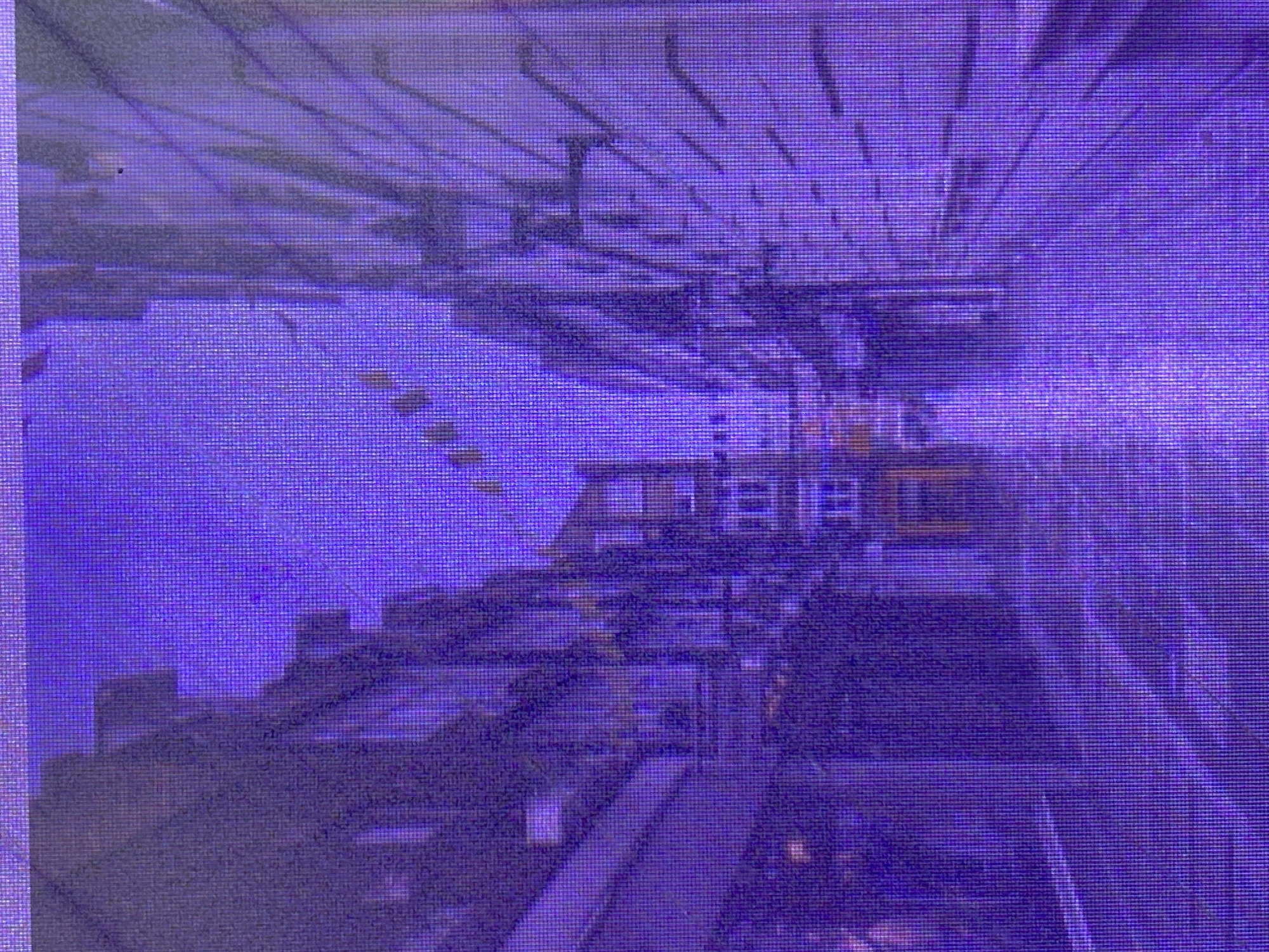 The media file depicts an interior scene, possibly a large warehouse or industrial space, bathed in a pervasive purple light. The architecture suggests a multi-level structure with visible beams and what appear to be walkways or conveyor belts. The overall impression is one of a somewhat aged or utilitarian environment.
Objects within the scene include large, dark, rectangular forms that could be machinery, storage containers, or construction elements. There are also lighter-colored structures that might be shelving units or smaller pieces of equipment. The repetitive horizontal lines across the image indicate a pixelated or digitally rendered quality, perhaps from a screen or a low-resolution capture.
No people are discernible in the image. The activity, if any, is not apparent due to the lack of movement or human presence. The time of day and weather are impossible to determine from the visual information provided. The location cue of Ikorodu, Nigeria, offers context for the type of industrial or commercial setting that might be found there, but no specific landmarks are visible to confirm the exact location.
There is no visible text in the image. The dominant purple hue and the grainy, pixelated texture create an abstract and somewhat disorienting visual experience, making it difficult to interpret specific details or evoke emotions beyond a sense of industrial scale and mystery.