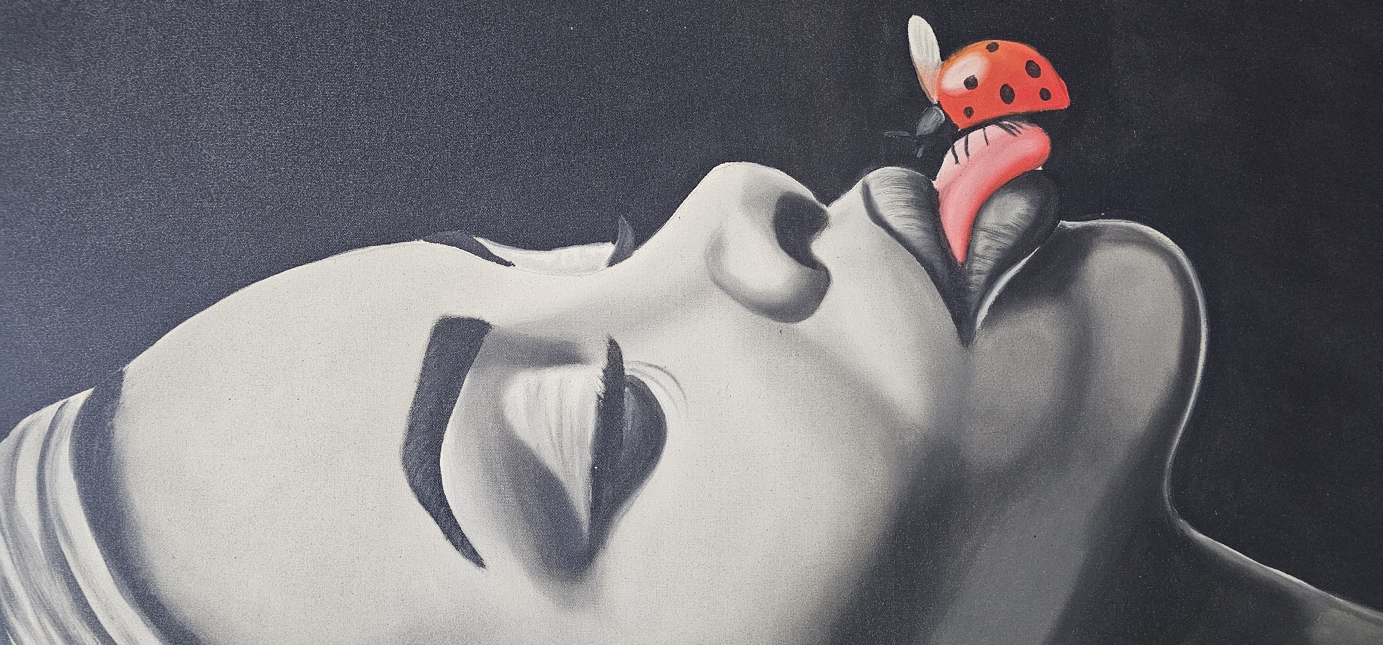 The image depicts an art piece, possibly a painting, featuring a woman's face rendered in grayscale. She is lying on her back with her eyes closed and her mouth slightly open. A ladybug, brightly colored in red with black spots, is perched on her tongue, which is also colored in a vibrant pink. The background is a solid, dark shade, emphasizing the face and the ladybug. There's no evidence suggesting the image was taken in the city of Denpasar, Indonesia, as no details about the city or local landmarks are visible.