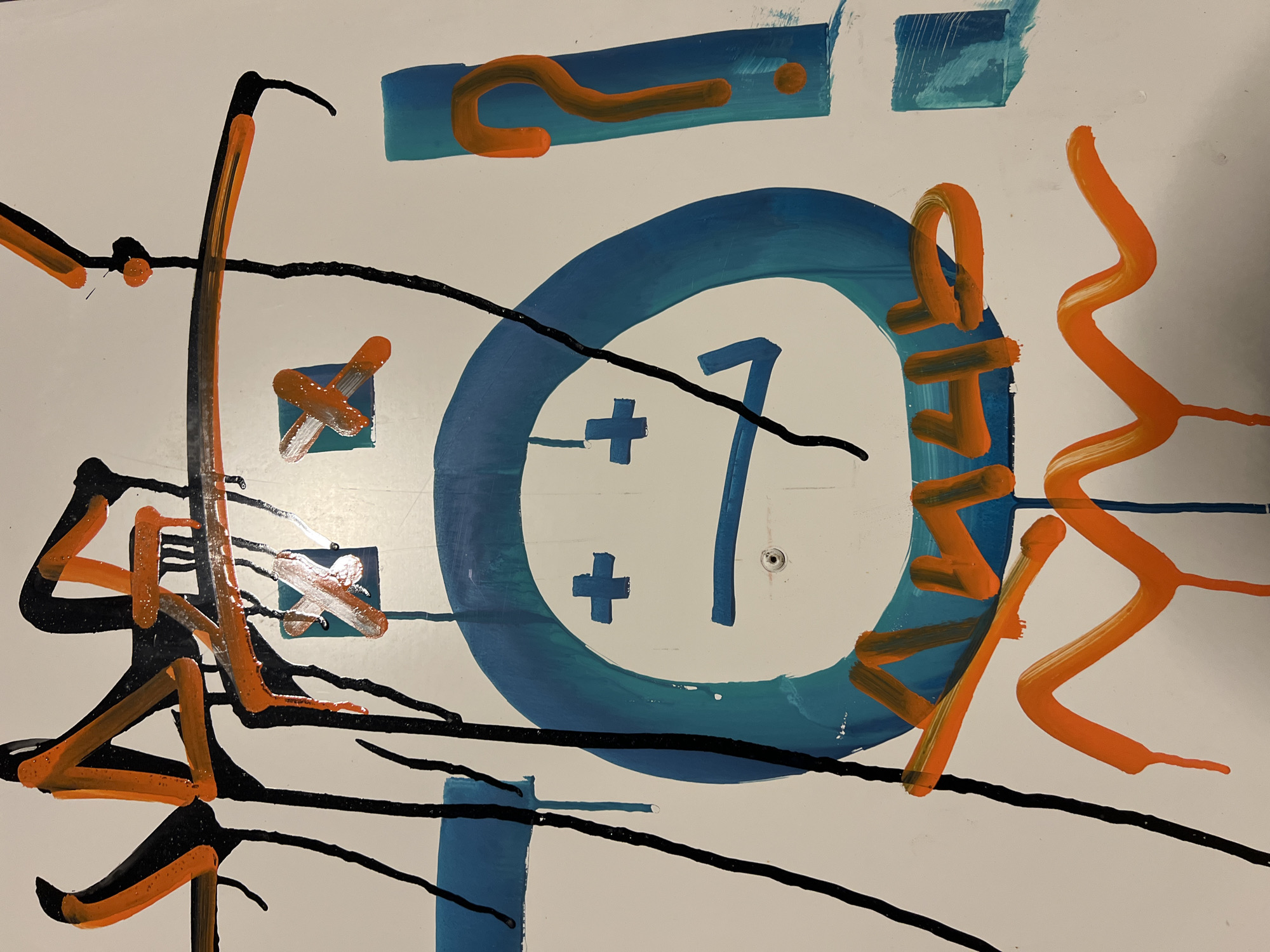 The image appears to be a close-up of an abstract artwork or graffiti on a white surface. The artwork consists of various shapes and lines in the colors blue, orange, and black. A blue circle with a white center containing a number "1" and a plus sign is a prominent feature. Other elements include orange question marks and squiggle lines. Black lines are randomly dispersed across the image. There is no information provided in the prompt to suggest the location of this image is Bečići, Montenegro.