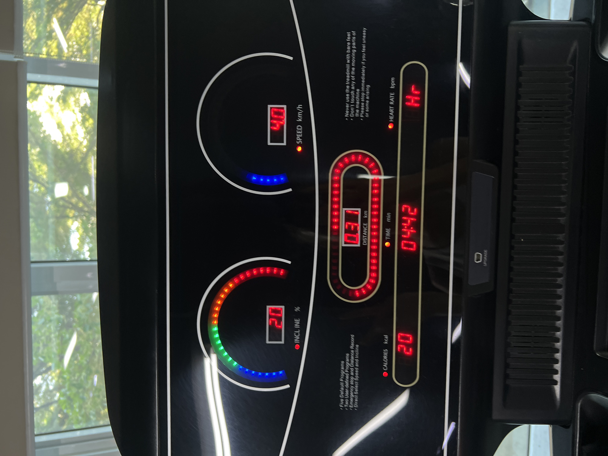 The image shows the console of a treadmill, likely in a home or gym setting, but the specific location in Nha Trang, Vietnam is unknown. The display shows a speed of 4.0 km/h, an incline of 20%, a distance of 0.31 km, a time of 4 minutes and 42 seconds, and 20 calories burned. The heart rate is not displayed, indicated by "Hr." The console also includes basic instructions and program options.