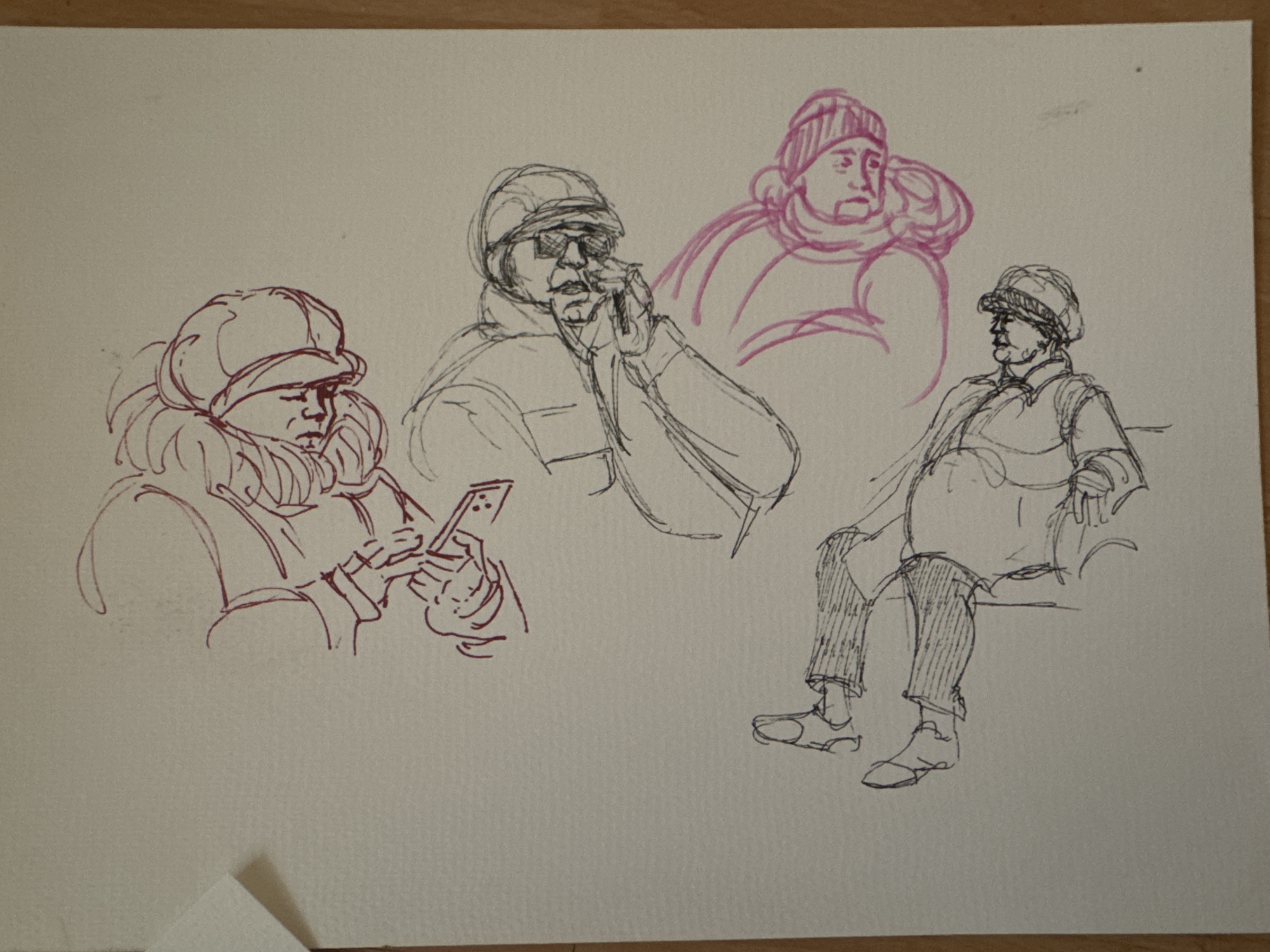 The image is a sketch of four people. The sketch is done in pen, using two different ink colors (red/pink and gray/black).
The first figure, on the left, is facing left and looking at a phone in their hands. They are wearing a hat and a large collared jacket. The second figure is facing forward, wearing sunglasses, and appears to be talking on a phone while holding it up to their face. The third figure is facing forward with a hat and scarf. The fourth figure is sitting down and wearing a hat.
The scene suggests a public place, possibly in a city, given the varied attire and actions of the individuals. Burgas, Bulgaria is not evident from the visual information.
