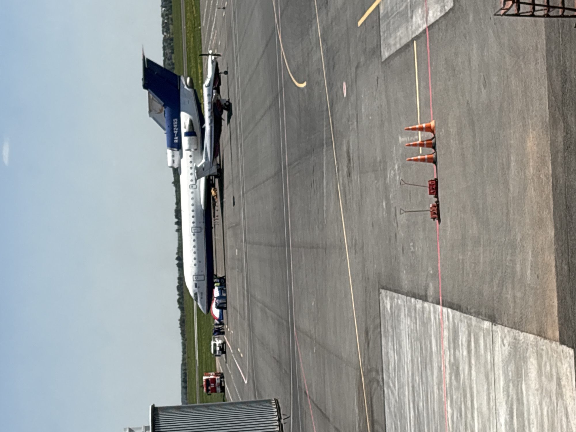 The image shows an aircraft parked on an airport tarmac. The plane has a white fuselage with a blue and white tail. The tail number reads "RA-42455". Airport ground vehicles are visible near the front of the aircraft. Orange cones are positioned on the tarmac. The location is likely Новое Мартьяново, Russia. The sky is pale blue.