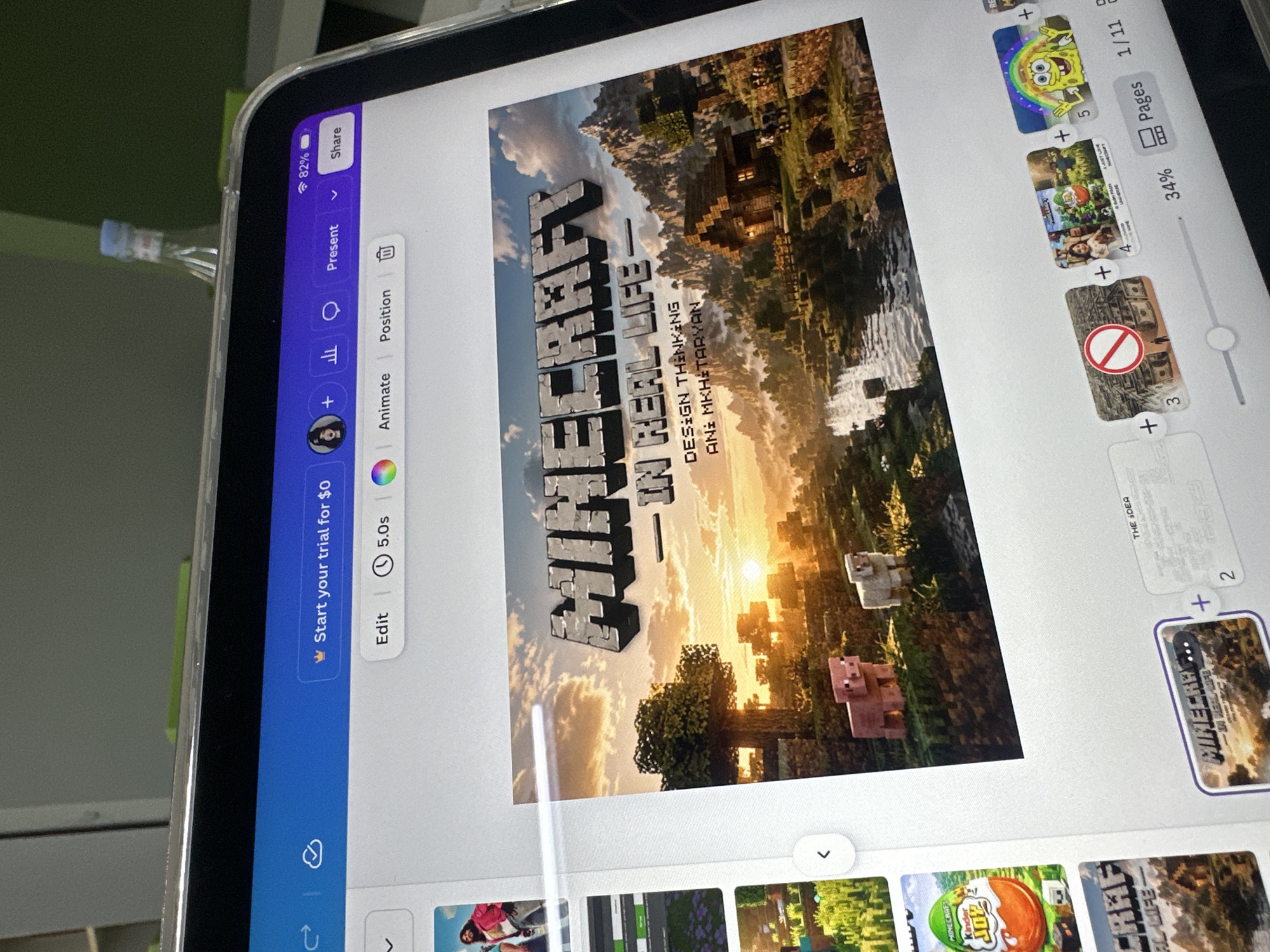 The image shows a tablet displaying a digital design of a Minecraft-themed cover titled "Minecraft - In Real Life," with the subtitle "Design Thinking" and authorship attributed to "Ani Mkhitaryan." The tablet's screen also displays a user interface, showing editing options, presentation settings, sharing options, and page thumbnails. Additional elements captured in the image include a portion of a water bottle and surrounding room details. There is no indication that the image was taken in Yerevan, Armenia.
