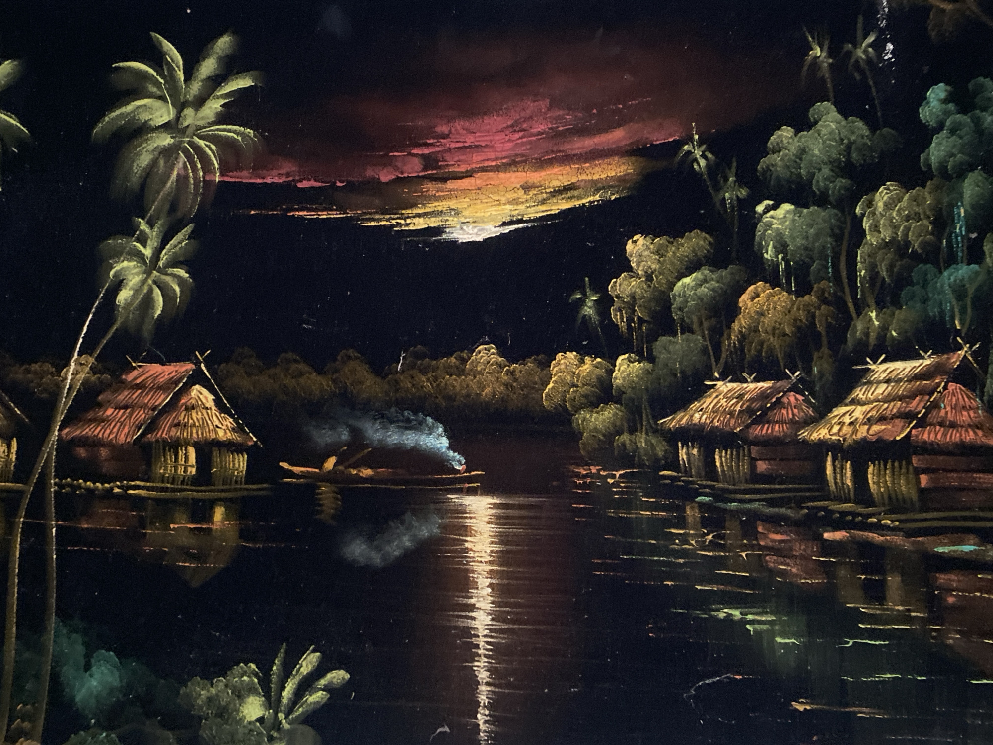 The image is a painting depicting a nocturnal river scene, possibly in a tropical location. Several stilt houses with thatched roofs are visible along the riverbanks. Lush vegetation, including palm trees, is present. A small boat with a light source is positioned in the middle of the river. The sky shows a dark gradient, with hints of pink and orange suggesting either sunset or sunrise. The river reflects the light from the sky and the houses. The painting has a slightly textured appearance, possibly due to the medium used. There is no specific evidence linking this image to Tinaquillo, Venezuela.