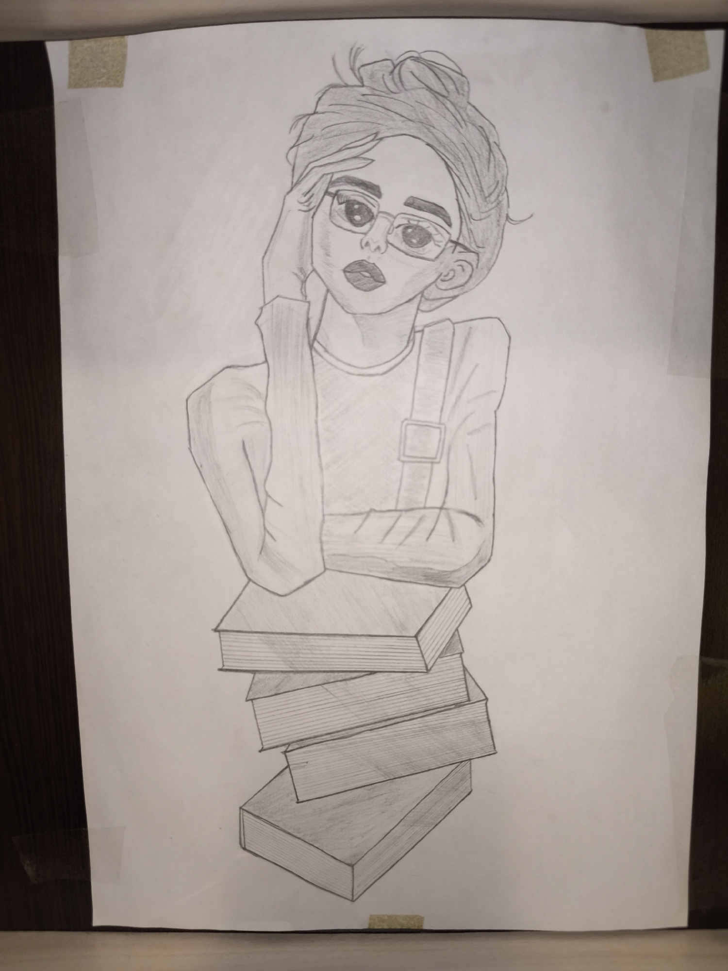 A pencil drawing of a young woman with her hair in a bun and glasses. She is leaning on a stack of books. The drawing is taped to a surface. There is no location information available.