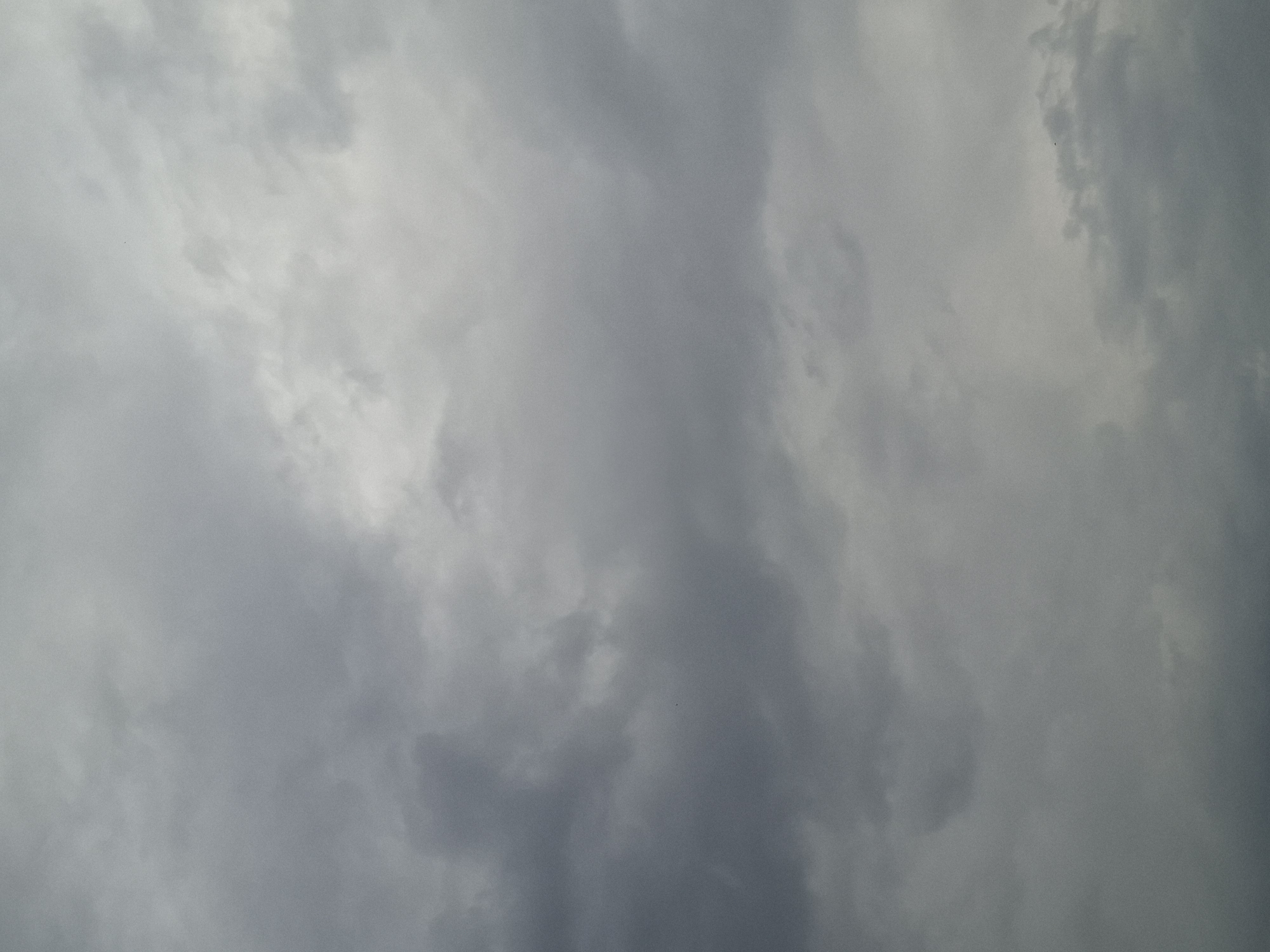 This media file is a photograph of a cloudy sky. The clouds are dense and range in color from light gray to dark gray, indicating overcast weather, possibly pre-storm conditions. There are no discernible objects, people, or structures in the image. The focus is solely on the texture and varying tones of the clouds, creating a sense of depth and atmospheric movement. The lighting suggests it is daytime, but the heavy cloud cover obscures direct sunlight, leading to a diffused and muted illumination. There is no visible text in the image. The scene is a generic sky, devoid of specific location cues beyond the provided context of Kazan, Russia, which does not manifest visually in the photograph itself. The overall mood is somber and perhaps a little foreboding due to the dark, heavy clouds.