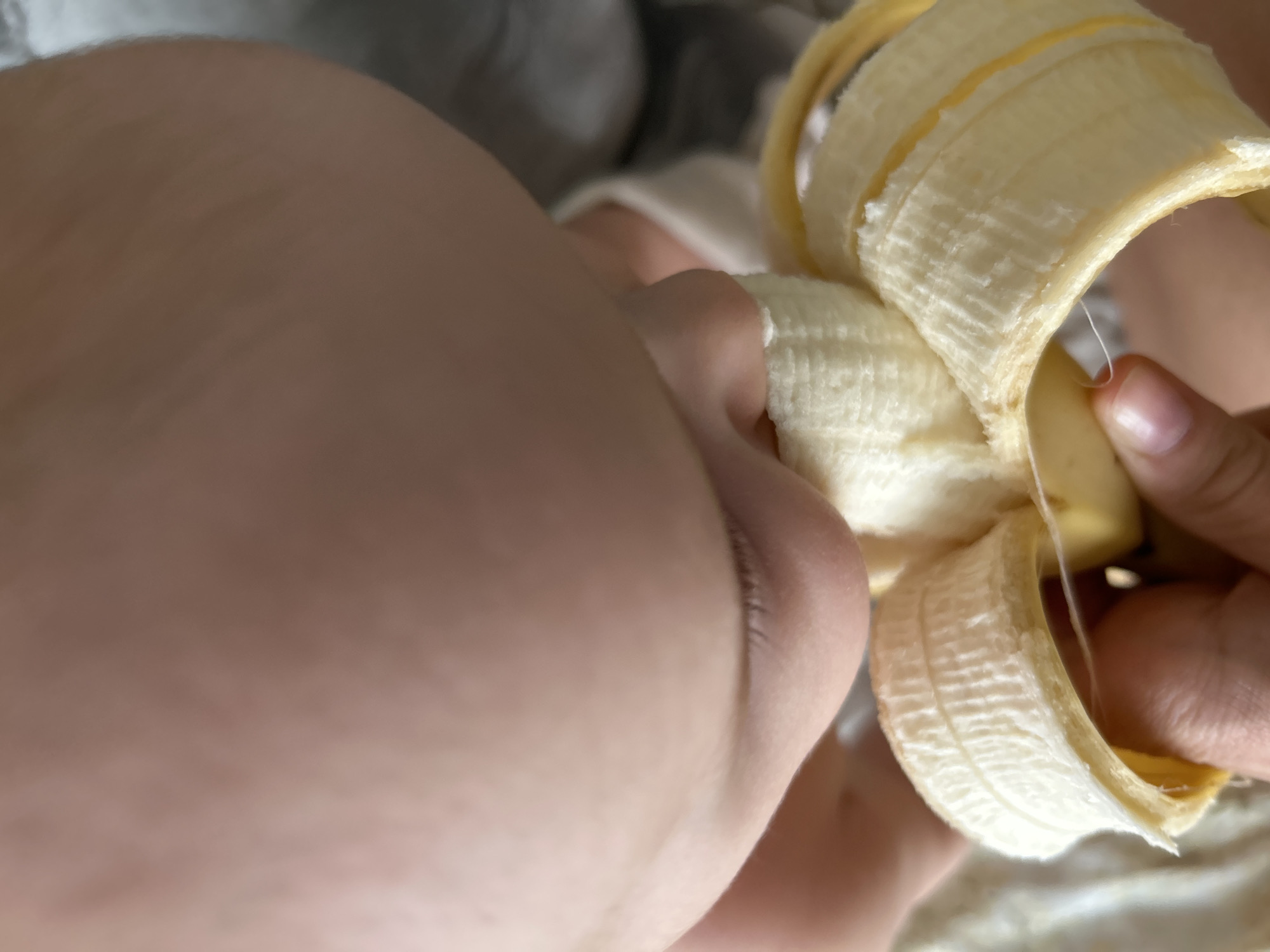 A close-up shot depicts a person peeling a banana. The banana peel is partially removed, revealing the fruit inside. The person's hands are visible holding and peeling the banana. The background is blurred and indistinct. There is no evidence to suggest that the image was taken in Moscow, Russia.