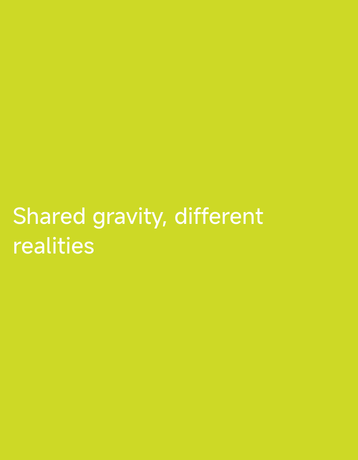 The image displays a uniform, solid chartreuse background. Positioned in the lower-left quadrant are two lines of white, sans-serif text. The first line reads "Shared gravity, different", and the second line, directly beneath and left-aligned with the first, reads "realities". The image is a digital graphic and does not depict a physical location, city, people, or complex objects.