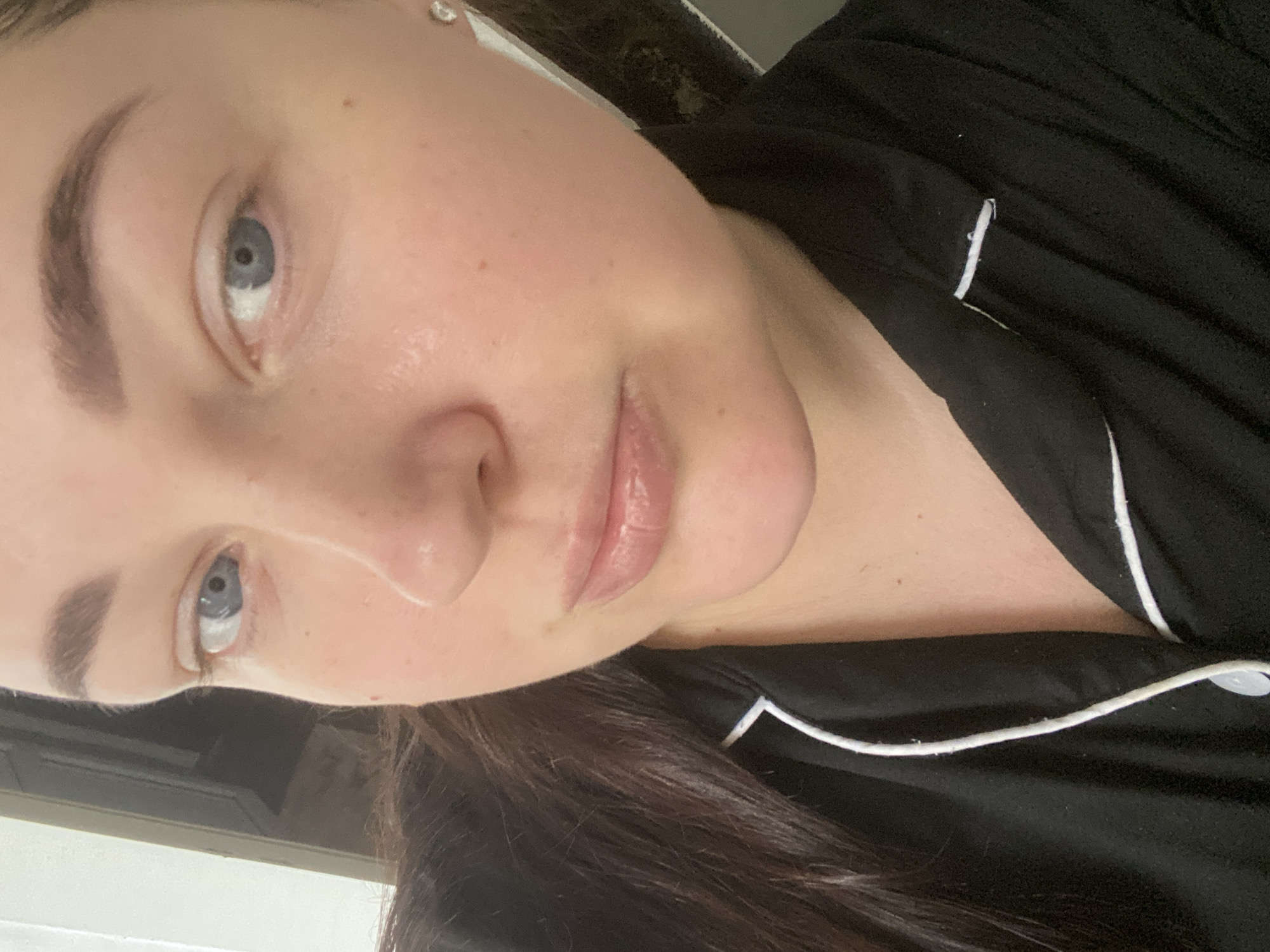 A close-up, angled shot of a fair-skinned woman with light blue eyes and brown hair. She is wearing a black pajama top with white piping. The background is out of focus and indistinct. No information suggests this image was taken in Sochi, Russia.