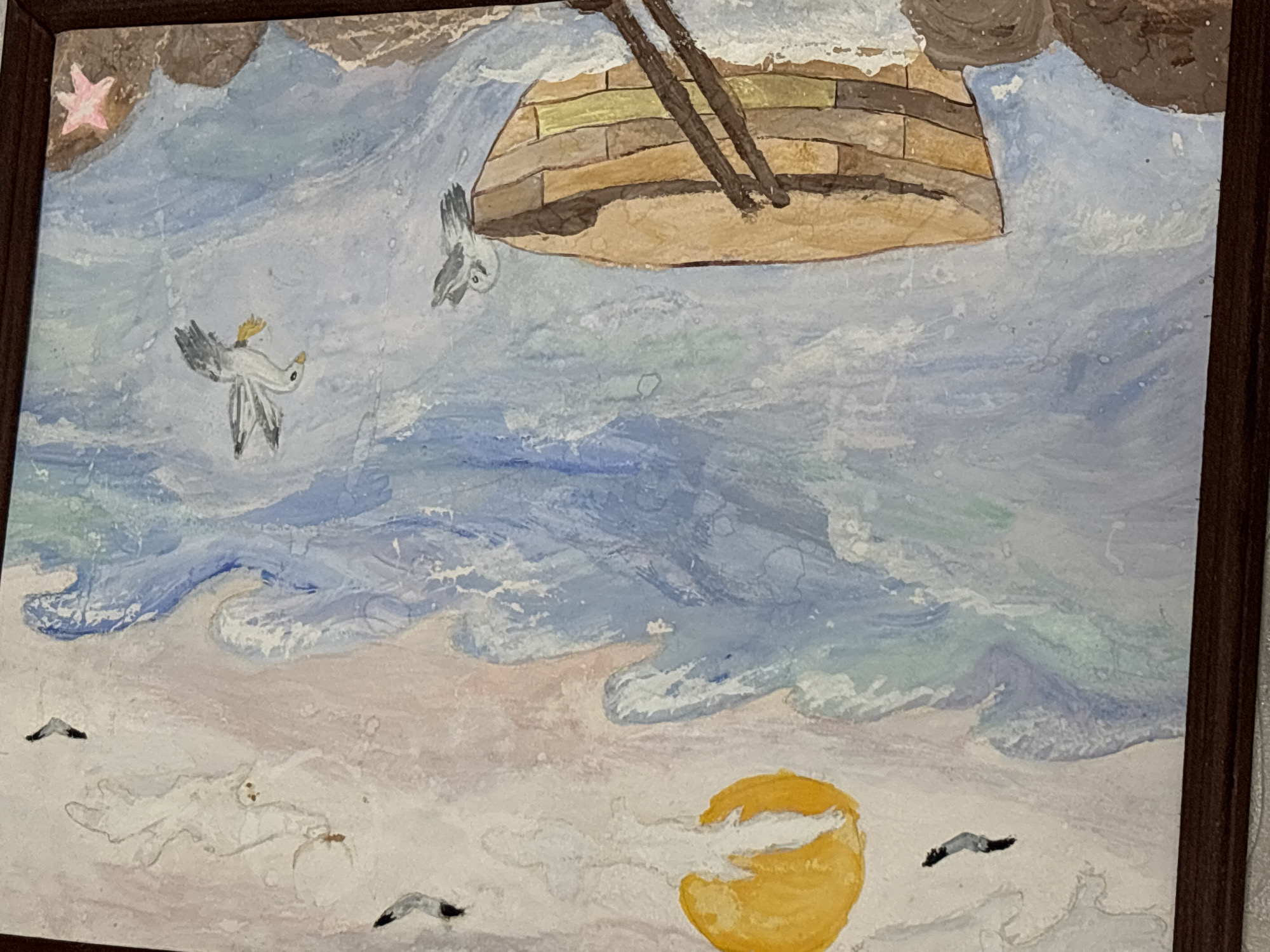 The image is a watercolor painting depicting a boat in choppy seas under a hazy sun. Several seagulls are present in the sky and near the boat. The foreground shows rocks and a starfish. The painting is framed in dark wood. There is no information in the image that suggests a specific location in Pavlodar, Kazakhstan.