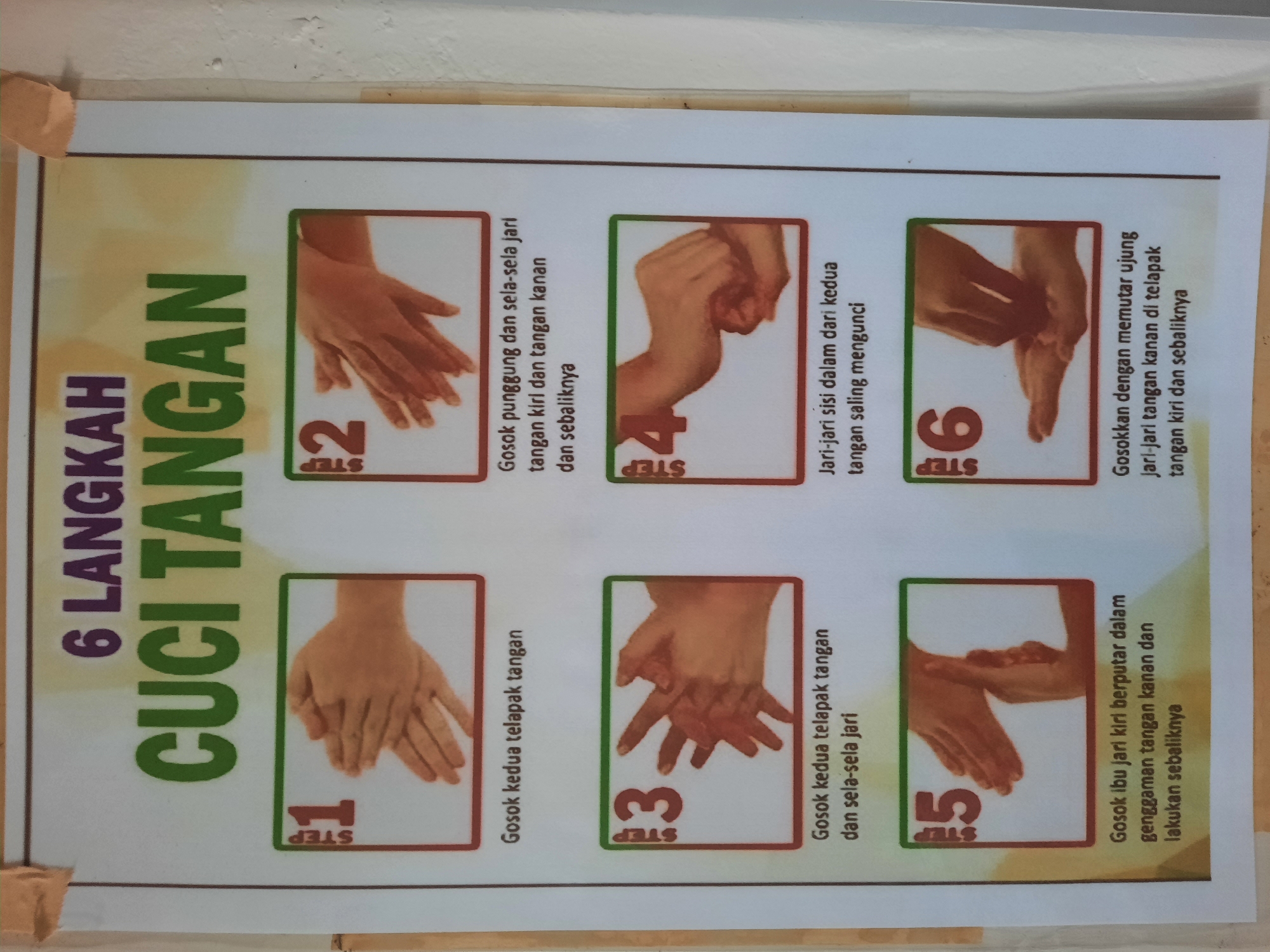 The image displays a poster with six illustrated steps on how to properly wash hands, titled "6 LANGKAH CUCI TANGAN" (6 Steps of Hand Washing). The poster is mounted on a light-colored, textured wall, possibly concrete, with visible imperfections. Two pieces of light brown tape are affixed to the top edge of the poster, securing it to the wall.
Each step is presented in a rectangular frame with a red border and a green border around the "STEP" number and illustration.
Step 1 shows two hands palm-to-palm, with fingers interlocked. The accompanying text reads "Gosok kedua telapak tangan" (Rub both palms).
Step 2 depicts the back of one hand being rubbed by the palm of the other, with fingers intertwined. The text says, "Gosok punggung dan sela-sela jari tangan kiri dan tangan kanan dan sebaliknya" (Rub the back and between the fingers of the left and right hands and vice versa).
Step 3 illustrates the palms of both hands being rubbed together, with fingers interlocked and slightly spread. The text reads, "Gosok kedua telapak tangan dan sela-sela jari" (Rub both palms and between the fingers).
Step 4 shows the fingertips of one hand being rubbed in a circular motion against the palm of the other hand, with fingers interlocked. The text states, "Jari-jari sisi dalam dari kedua tangan saling mengunci" (Fingertips of both hands interlock).
Step 5 shows one thumb being clasped and rotated within the palm of the other hand. The text translates to, "Gosok ibu jari kiri berputar dalam genggaman tangan kanan dan lakukan sebaliknya" (Rub the left thumb rotating in the palm of the right hand and do the opposite).
Step 6 shows the fingertips of one hand being rotated in the palm of the other hand. The text reads, "Gosokkan dengan memutar ujung jari-jari tangan kanan di telapak tangan kiri dan sebaliknya" (Rub by rotating the fingertips of the right hand on the left palm and vice versa).
The lighting in the image appears to be ambient, casting soft shadows. The overall scene suggests an educational or public health display. Without further context or visible landmarks, the specific location within Lhokseumawe, Indonesia, cannot be determined, but it is likely in a public space such as a school, clinic, or community center.