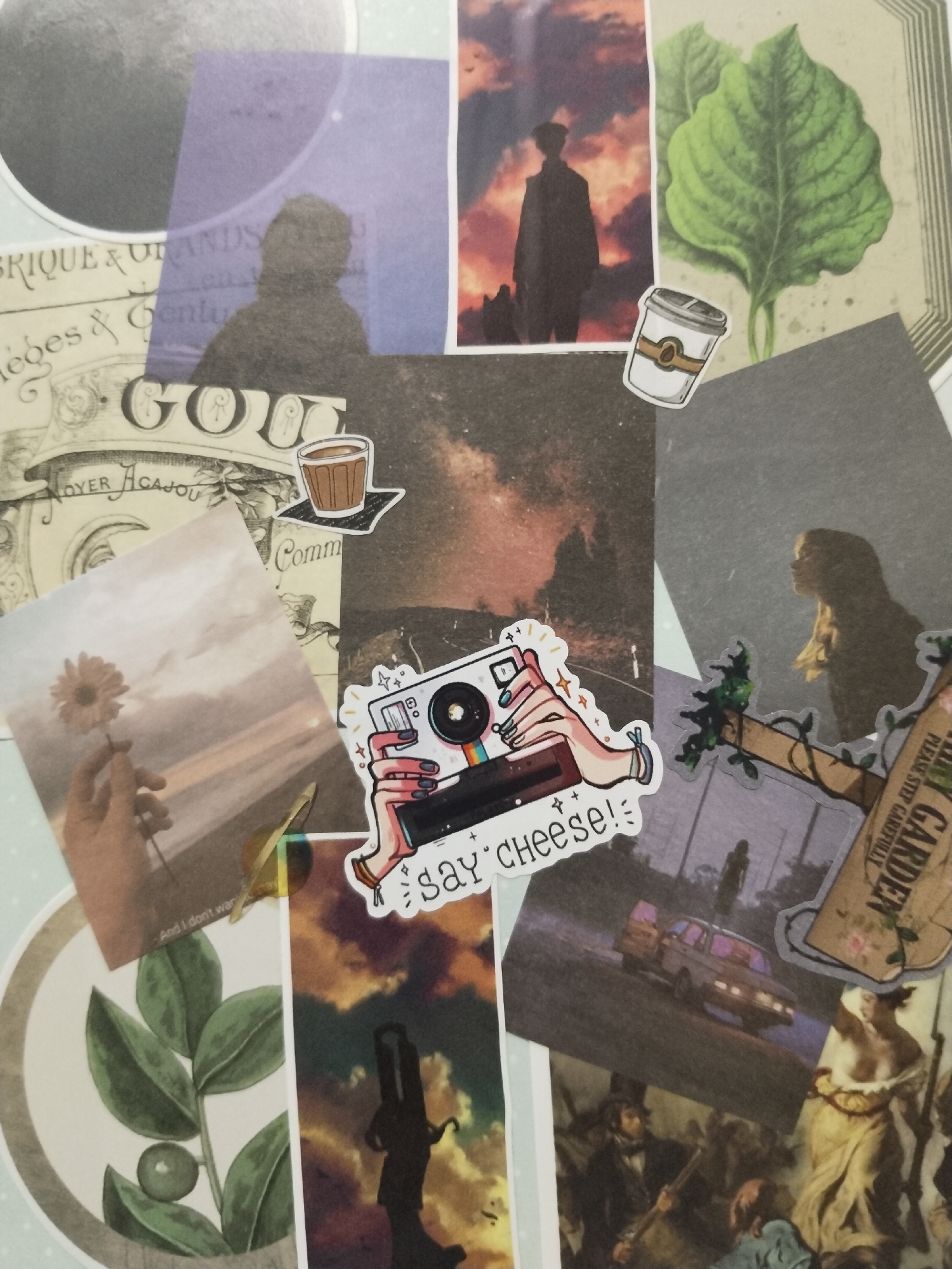 The image is a collage of various photographs and cutouts, featuring a diverse range of subjects and styles. It includes a silhouette of a person against a fiery sky, a close-up of green leaves, a coffee cup sticker, and a Polaroid-style image of a hand holding a flower. There's also a sticker of a hand holding a camera with the text "say cheese!". Other elements include a portion of what appears to be an old map or document with text like "RIQUE & URANDS", and a faded image of a landscape with a car and a silhouetted figure in the distance. A classical painting fragment depicting figures is also visible. The overall impression is a collection of personal mementos and artistic inspirations.
There is no information in the image that provides any indication of its location in the city of Krasnoyarsk, Russia.