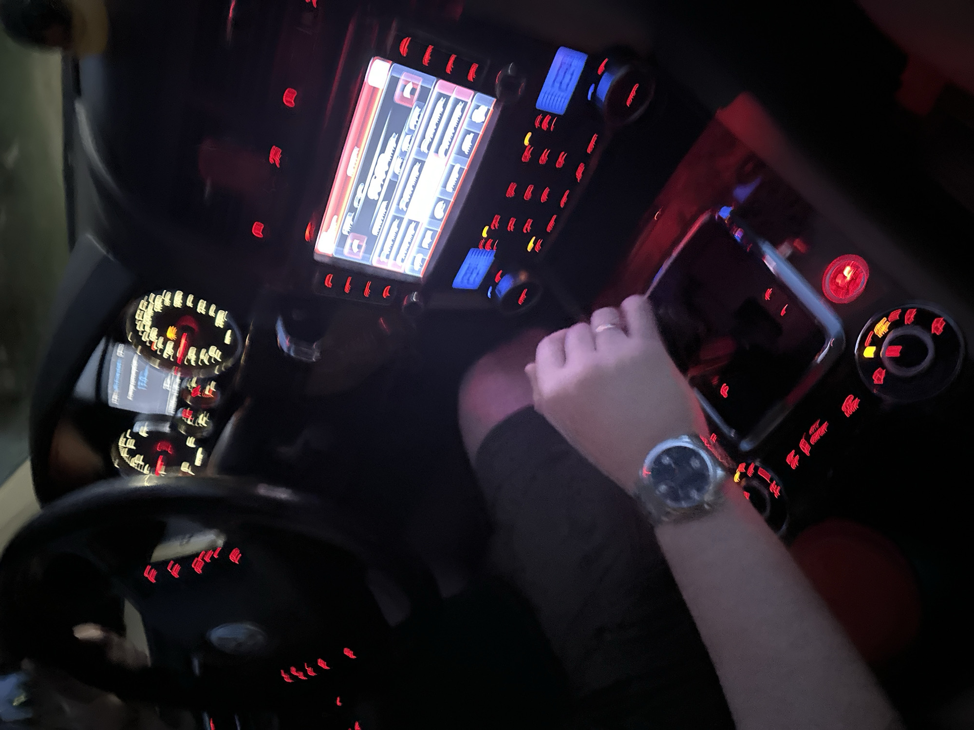 A person wearing a watch and a ring is seated in the driver's seat of a car. The car's dashboard is illuminated, displaying various controls and a screen showing a map. The steering wheel is in the lower left of the frame. The image appears to be taken at night or in low light conditions. The city of Nizhny Novgorod, Russia, is not identifiable based solely on the provided image.