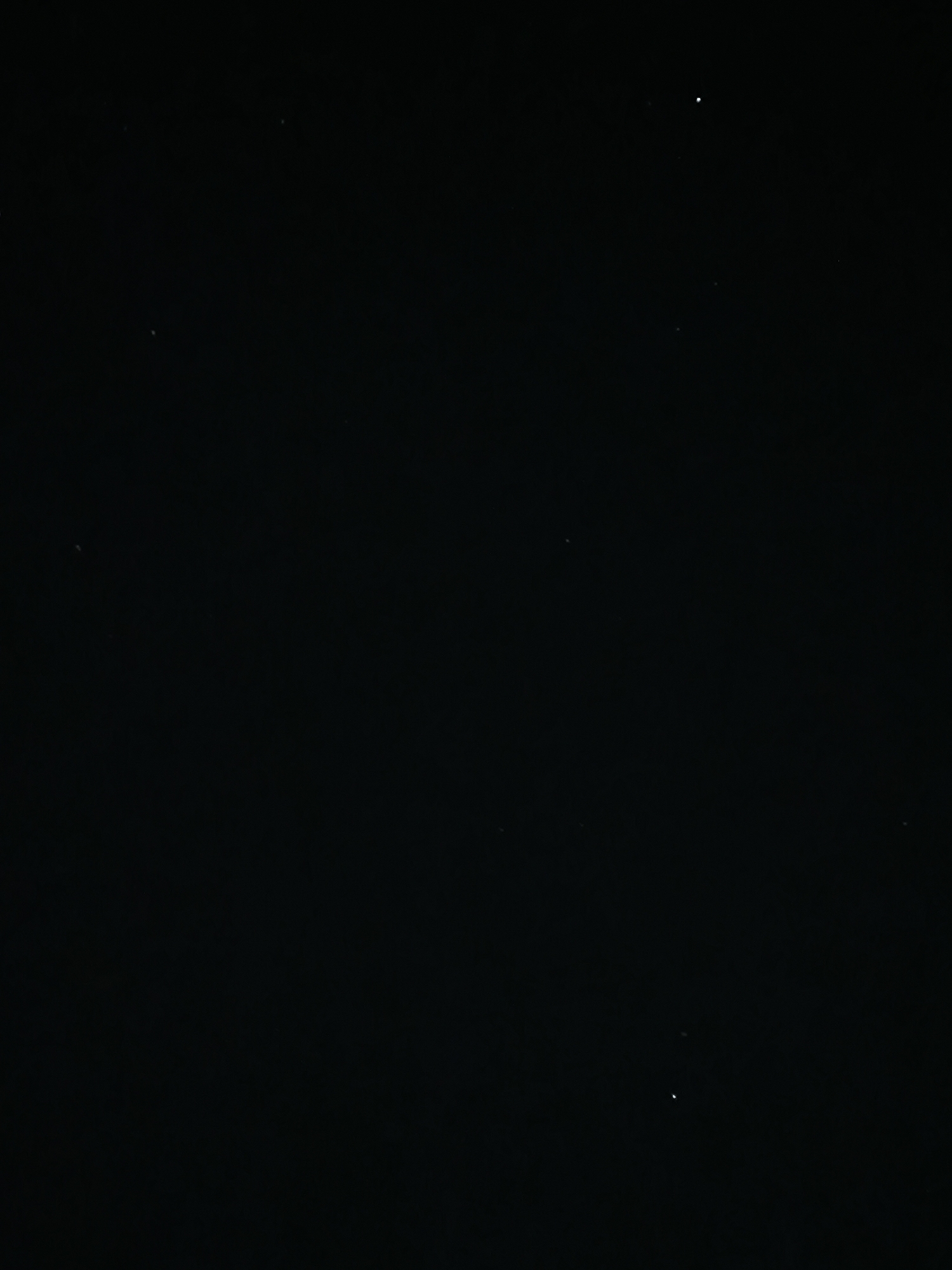 The image is a black photograph with a few small white dots, which appear to be stars or distant lights. The overall impression is of a dark, possibly nighttime, scene. There are no discernible landmarks or features that would indicate a specific location within Chișinău, Moldova. The image is devoid of any human presence, objects, or actions. The environment is entirely black, suggesting a lack of ambient light.