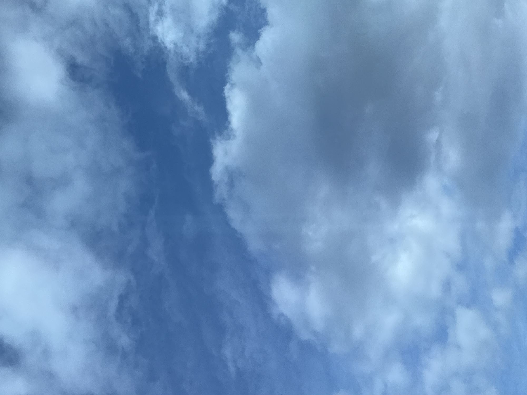 This is an outdoor, full-frame, eye-level shot of a bright blue sky filled with scattered clouds. The clouds are white and gray, with some appearing wispy and others more dense and billowy. The image captures the natural light of the sky, with no man-made structures or subjects visible. The scene is consistent with a clear day in Tallinn, Estonia.