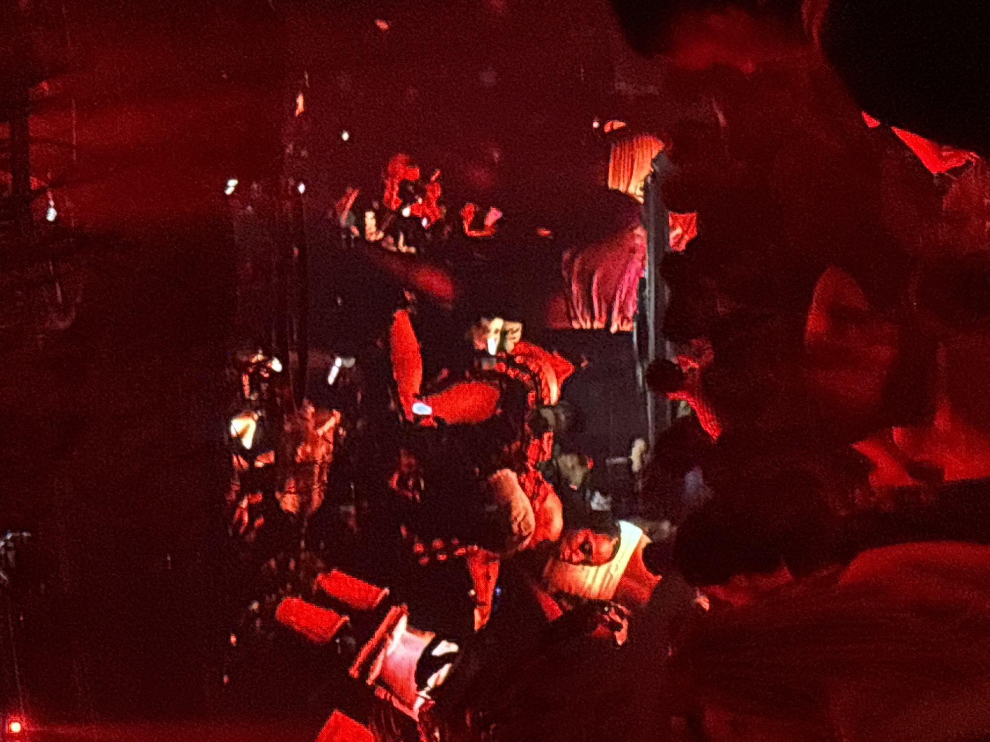 In a dimly lit venue, illuminated by a predominantly red ambient light, a DJ is seen behind a console, likely performing at a music event. The DJ appears to be operating turntables and a mixer, suggesting a live performance or party setting. The crowd, mostly obscured by the low lighting and the angle of the shot, is a dark silhouette against the vibrant red backdrop, indicating a gathering of people enjoying the music. The overall atmosphere is energetic and immersive, typical of a club or concert venue. The image is undated and unlocated, however it may have been taken in a popular nightlife spot within the city of North Jakarta, Indonesia, known for its vibrant entertainment scene.