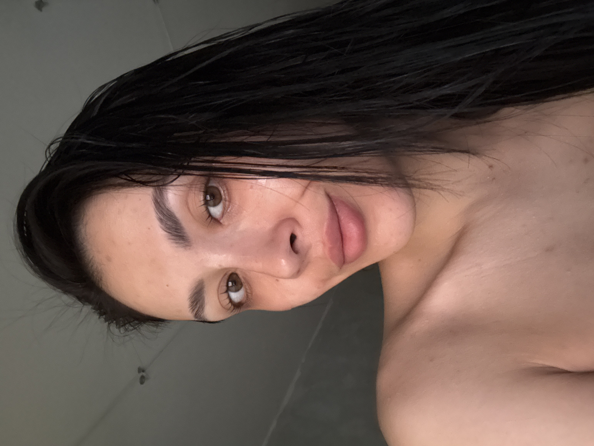 A selfie of a woman with dark, wet hair. The woman has brown eyes and full lips. The background appears to be a bathroom with tiled walls. The location is unknown and there is nothing to indicate that this image was taken in Votkinsk, Russia.