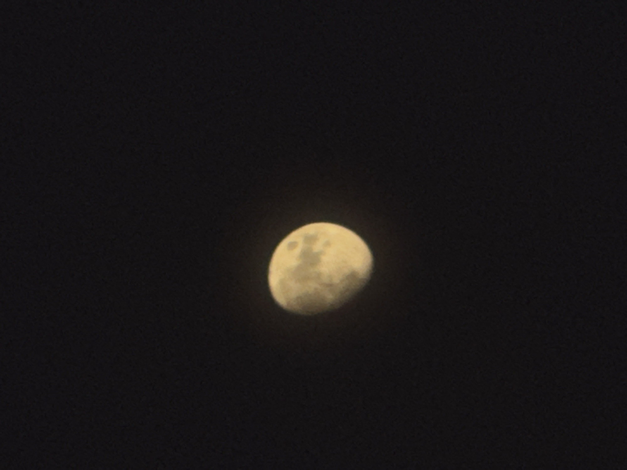 This is a photograph of the moon against a dark night sky. The moon is partially illuminated, showing craters and surface details. It is a cool, clear night, typical of the region. The image appears to have been taken with a moderate zoom, bringing the moon into focus against the vast expanse of space. There are no people or man-made objects visible in the frame. The scene is serene and focuses entirely on the celestial body. The setting is likely outdoors, in an area with minimal light pollution to allow for a clear view of the moon.