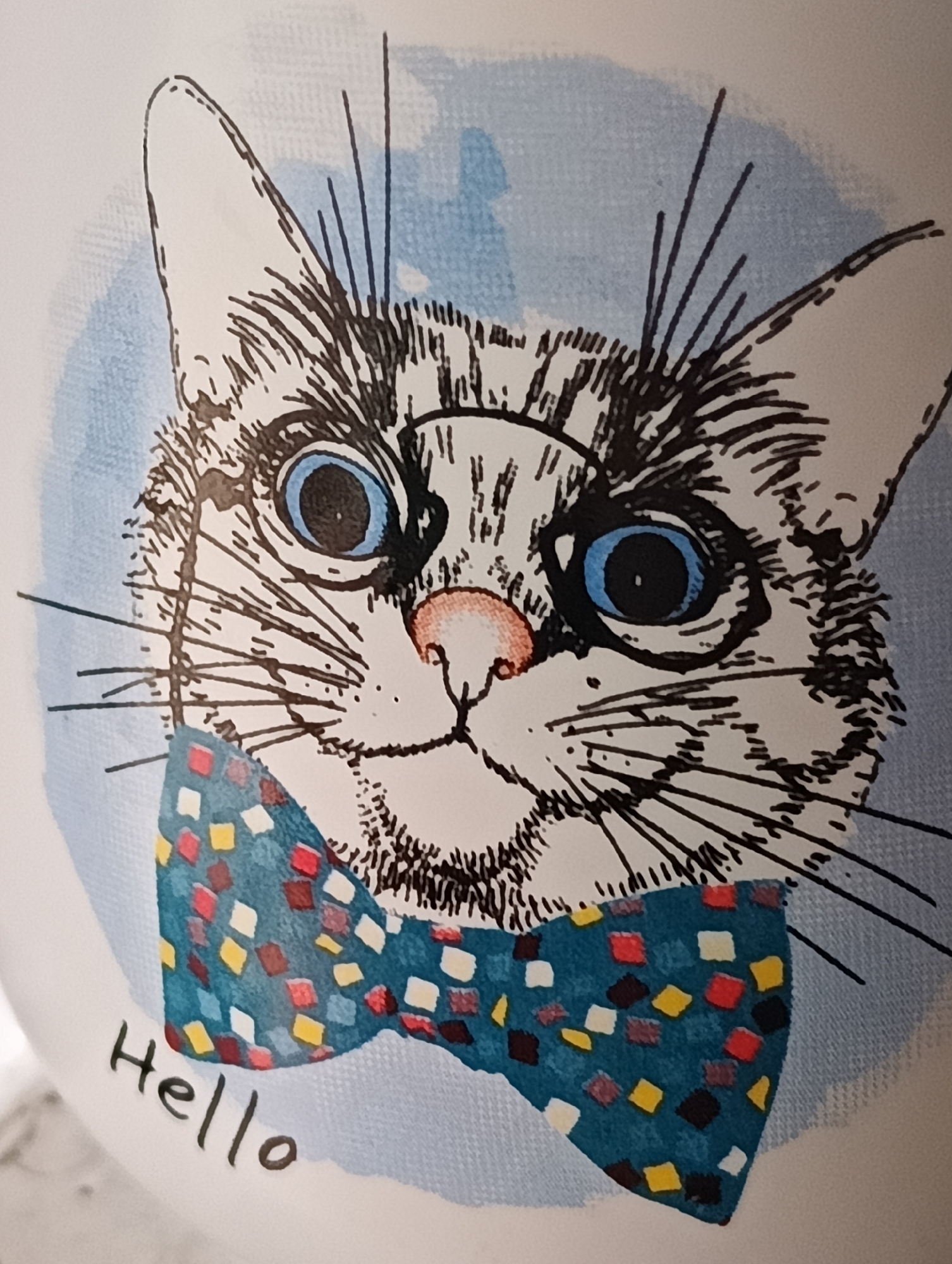 This is a close-up, full-frame, eye-level, medium shot of a drawing of a cat's face with a bow tie and the word "Hello" written below. The cat is sketched in black and white with blue eyes and a pink nose. It is wearing a blue bow tie with a colorful diamond pattern. The background is a light blue wash. The word "Hello" is written in black cursive script below the bow tie.