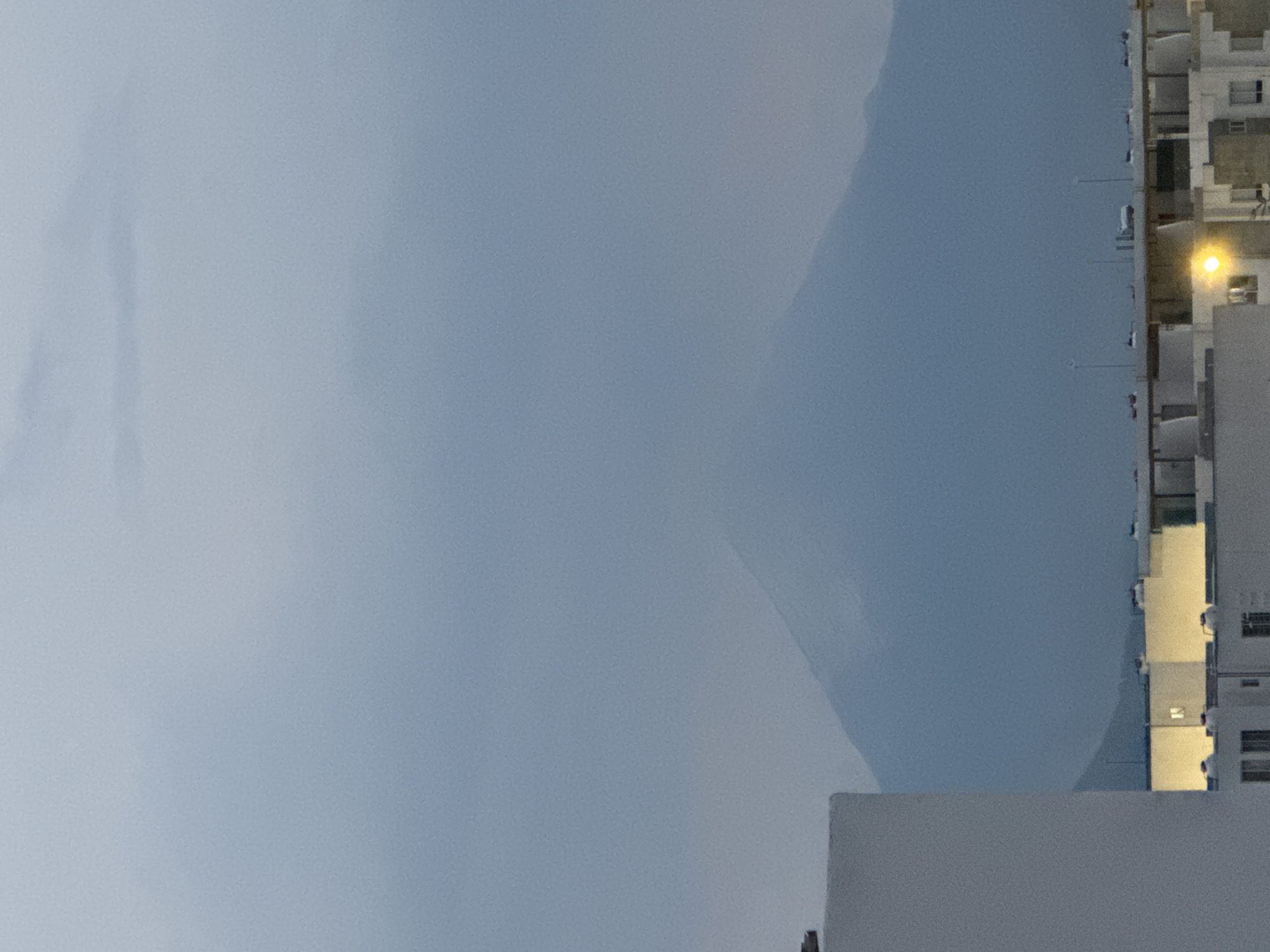 The image shows a view from the city of San Francisco Ocotlán (Ocotlán), Mexico, with a building visible on the right. The building appears to be tall with multiple windows and a light shining from within. The left side of the image is filled with a cloudy or overcast sky. The overall scene appears to be taken during the day, possibly in the early morning or late afternoon.