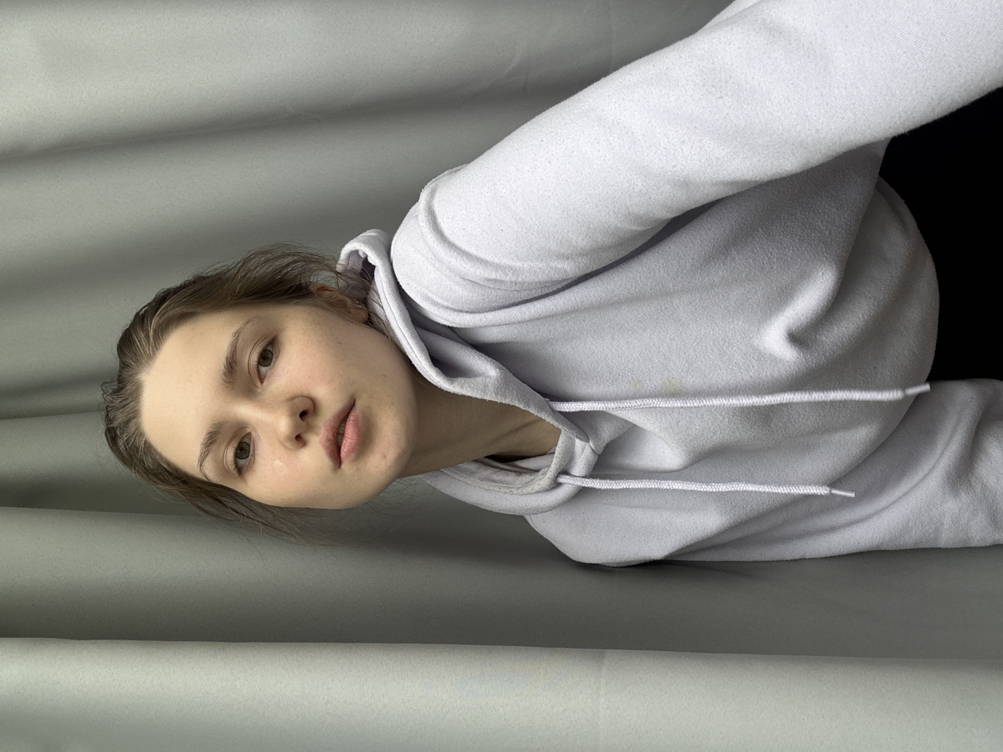 A woman wearing a white hoodie is visible in the image. The background features a grey curtain. The location in the city of Saint Petersburg, Russia is not determinable from the image.