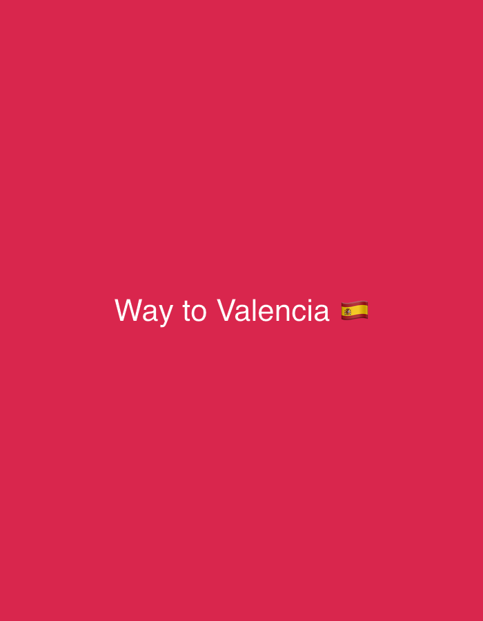 The image depicts a digital graphic on a solid magenta-red background. White text, "Way to Valencia", is centered horizontally in the lower-middle area of the frame. Immediately following this text is a Spanish flag emoji. The scene, entirely composed of these graphic elements, is located in Almenara, Spain. There are no individuals, physical objects, actions, interactions, or discernible environmental details present beyond the text and emoji on the colored background.