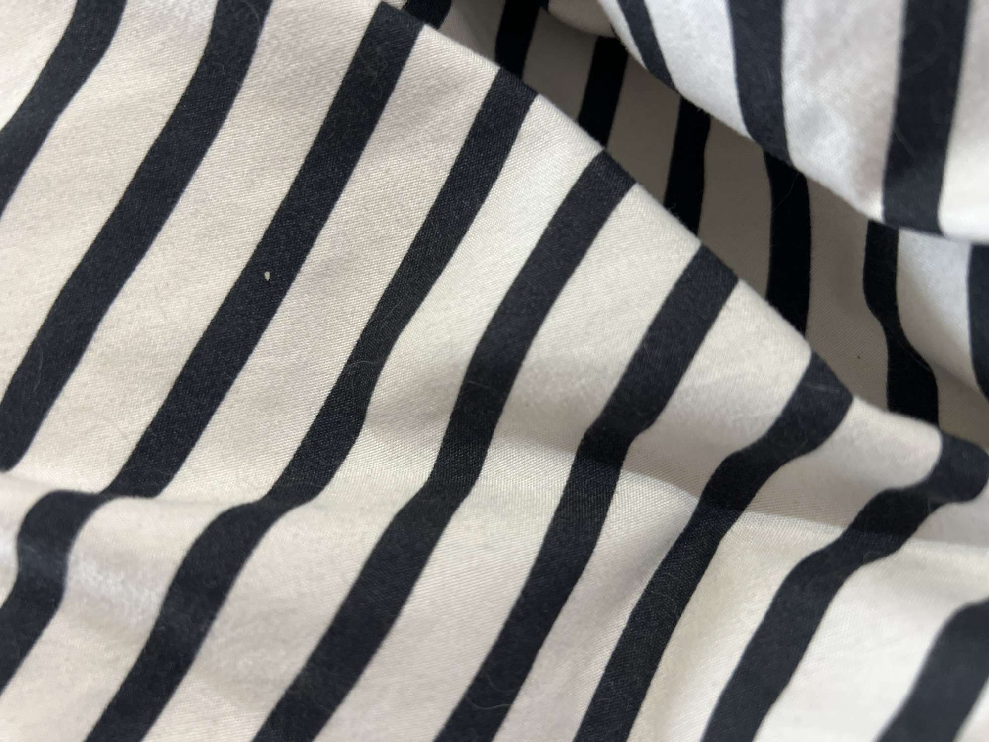 The image shows a close-up of a black and white striped fabric. The fabric is wrinkled and folded, creating a sense of depth and texture. The stripes are of equal width and run diagonally across the frame. The image does not include any information about people, actions, or the location of Gradishte, Bulgaria.