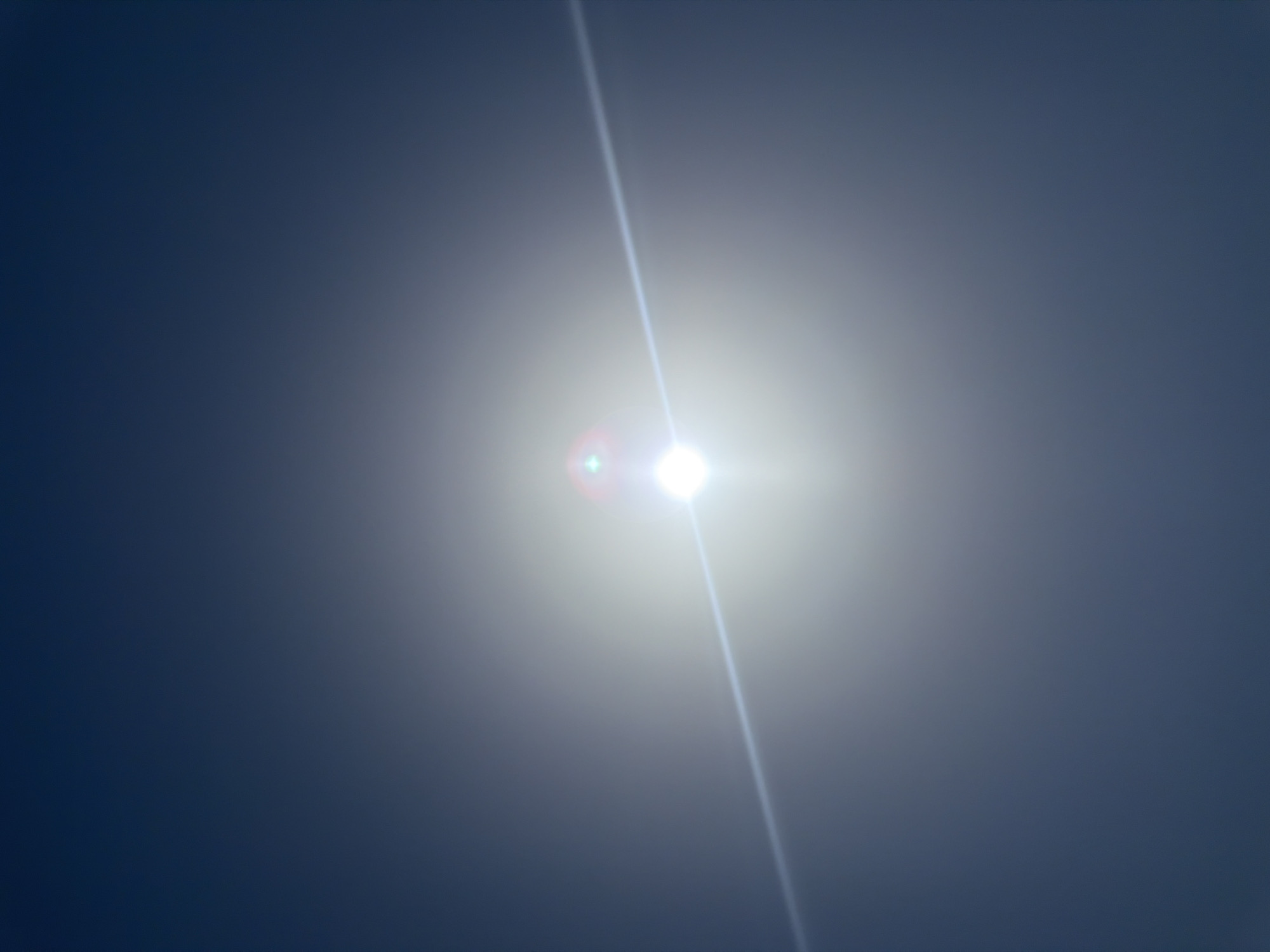 The image depicts a bright sun and a lens flare against a dark blue sky. There is a diagonal line of light extending from the sun across the image. The sky appears clear, with no clouds or other celestial bodies visible. The overall impression is of a bright, sunny day.
This image was taken in Sharm El Sheikh, Egypt. Sharm El Sheikh is a popular tourist destination located on the southern tip of the Sinai Peninsula, on the coast of the Red Sea. The city is known for its beautiful beaches, coral reefs, and vibrant nightlife. The clear skies and bright sun are typical of the region's climate.