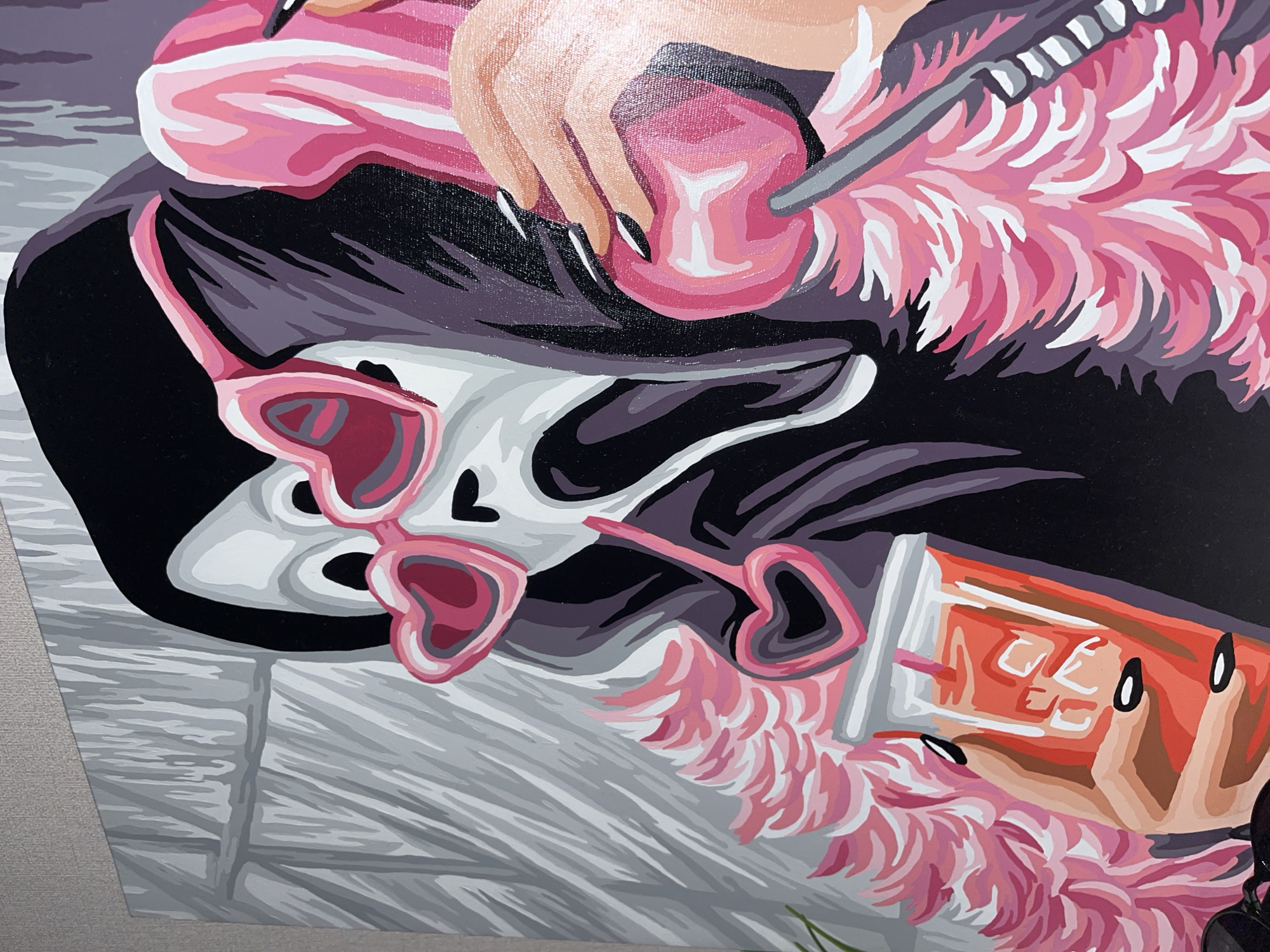 The image is a close-up painting of a stylized scene. A hand with long, black nails holds a pink, lollipop-shaped object. Fluffy pink material is visible near the hand and lollipop. Below, a pair of heart-shaped sunglasses sits on a grey surface with lines, possibly a table or floor. A pink and white object, possibly a tube or package, rests to the side. The background contains black and grey hues. There is no indication the location of this scene is in Krasnodar, Russia.