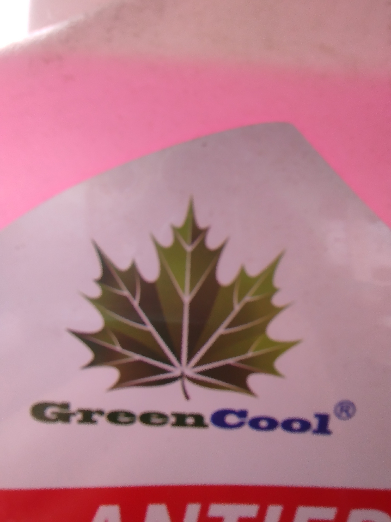 The image shows a close-up of a product label. The label features a stylized green maple leaf logo. Below the logo, the text "GreenCool®" is printed in dark green and blue. A red band is visible at the bottom of the image with partially obscured white text that appears to be part of a product name or description. The background is out of focus and appears to be a pale pink surface. The image appears to be taken indoors, possibly in a retail or domestic setting. There is no information in the image that can be used to determine its location in Крывасельскі сельскі Савет, Belarus.