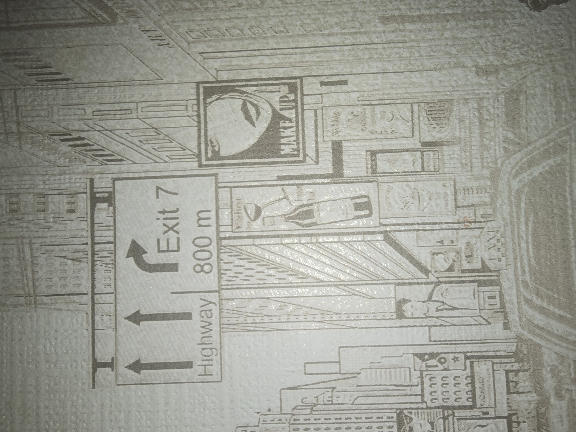 The image is a black and white drawing of a city scene, possibly a mural or wallpaper. It depicts buildings, a street sign, and several advertisements. The street sign indicates "Highway" and "Exit 7" with arrows pointing in different directions. One advertisement features a close-up of a woman's face with the text "MAKE UP". Another shows a bottle and a wine glass. There are also images of people, including a man in a suit and what appears to be a taxi. The drawing style is detailed, with a focus on architectural elements and commercial imagery. The text on the image is in English. The location in the city of Ulan-Ude, Russia, is not identifiable from the provided image, as it contains no markings or contextual clues that would indicate this specific geographic location.