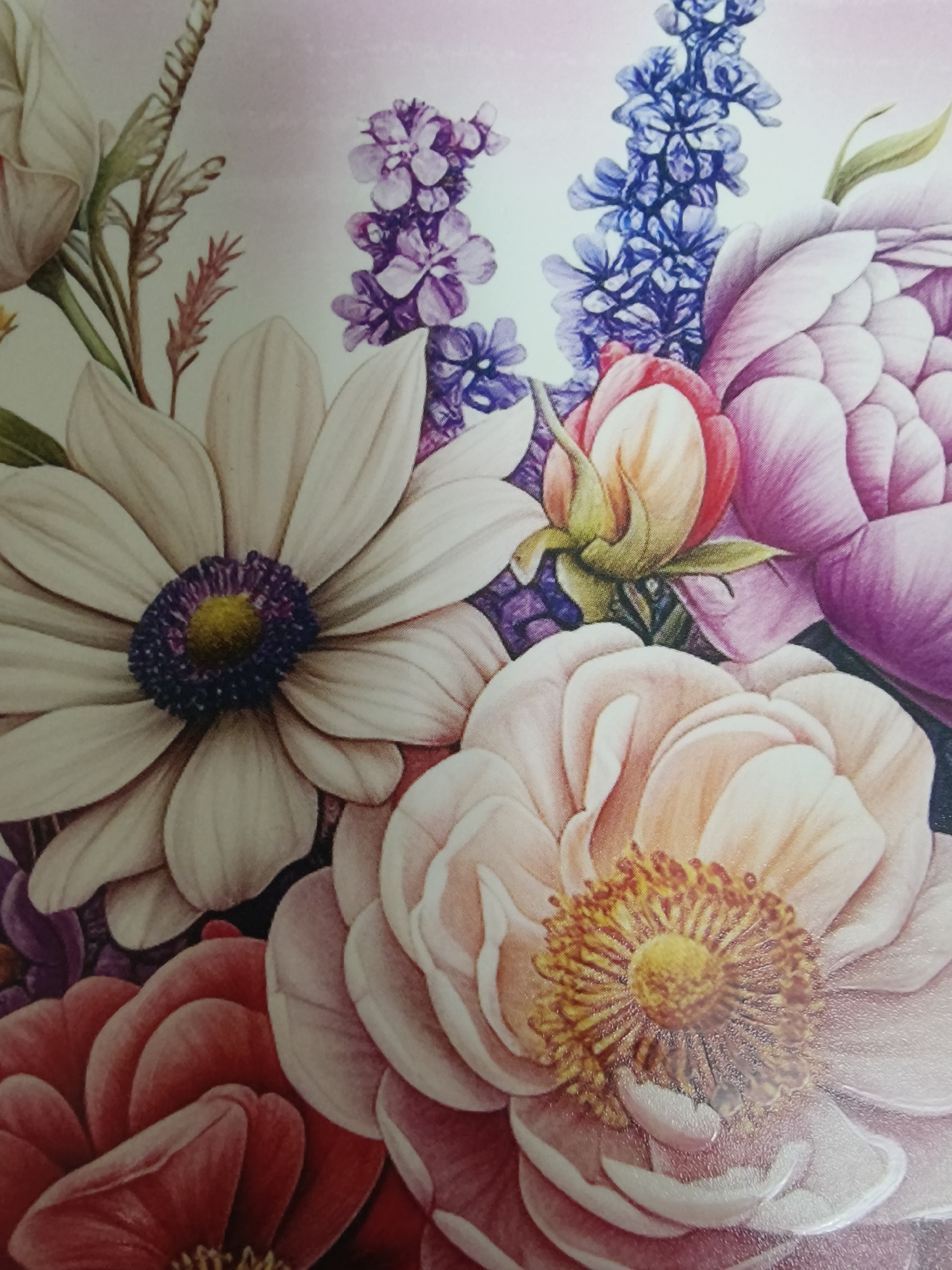 The image is a close-up of a bouquet of flowers in various shades of pink, purple, white, and blue. A large white daisy-like flower with a dark purple center is in the upper left. Pink peonies and buds are clustered towards the center and right, with some having peach undertones. There are also purple and blue spiky flower clusters in the background. The overall background is a soft, light pink. There is no indication of the city of Kryvyi Rih, Ukraine or any other specific location. The focus is solely on the floral arrangement. There are no people visible.