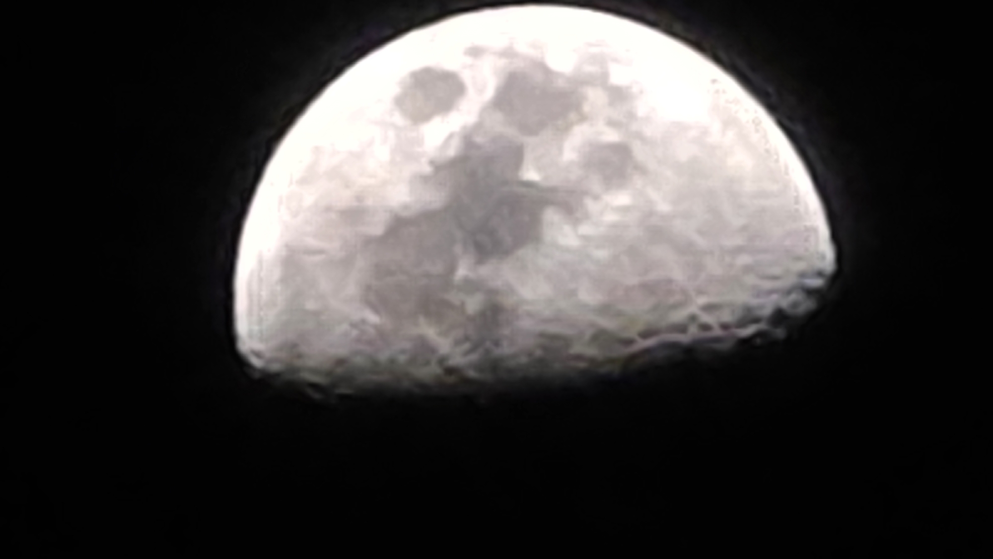 The image shows a waxing gibbous moon against a black background. No city or location information is discernible in the image.