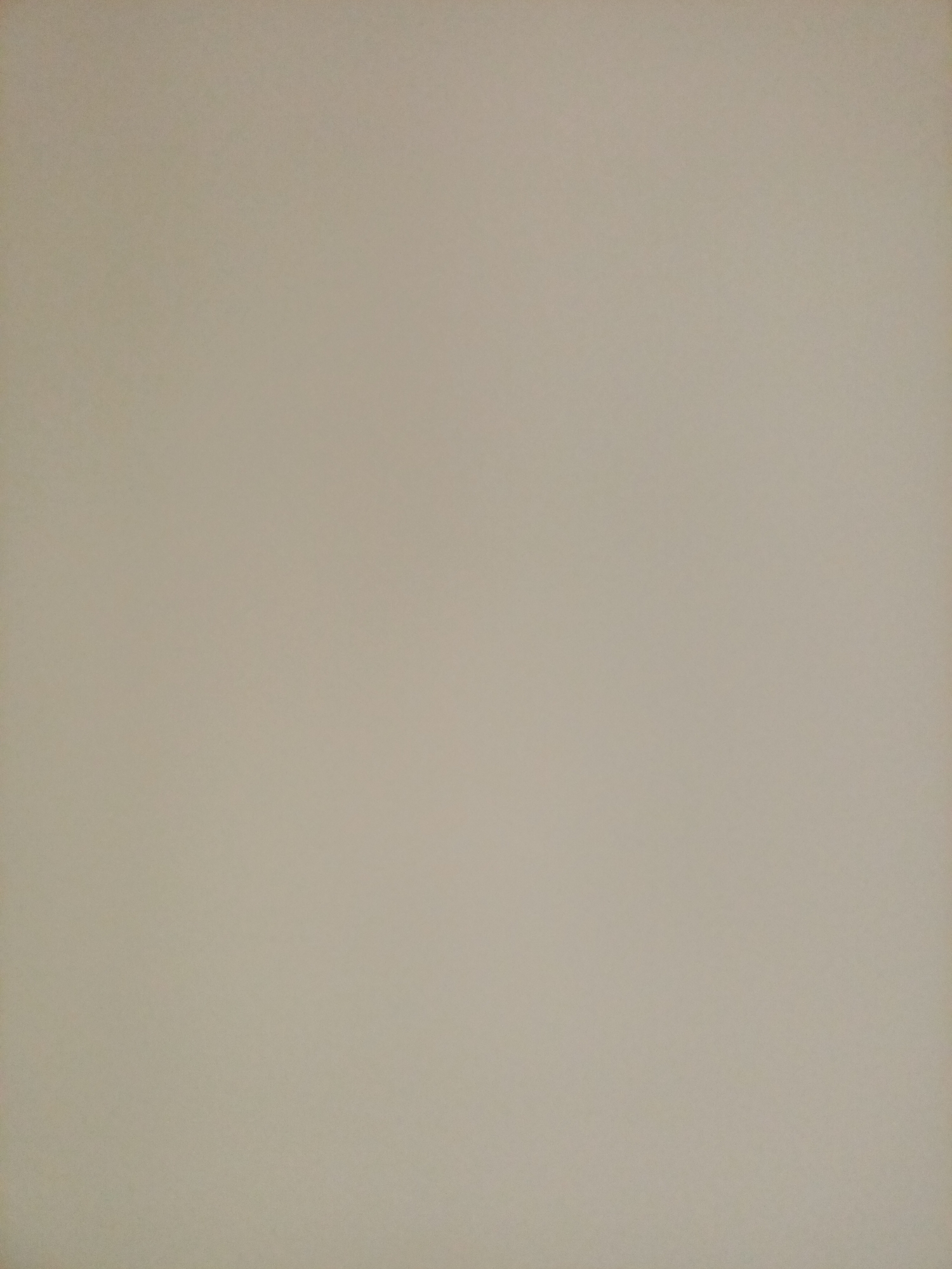 This is a full-frame, eye-level, medium shot of a plain, beige-colored wall. There are no discernible objects, people, or actions depicted in the image. The lighting is even and appears to be artificial. The image quality is average, with some slight graininess visible. The background is uniformly textured and shows no signs of damage or wear. The scene is devoid of any specific environmental context that would suggest a location in Rostov-on-Don, Russia, or any other city.