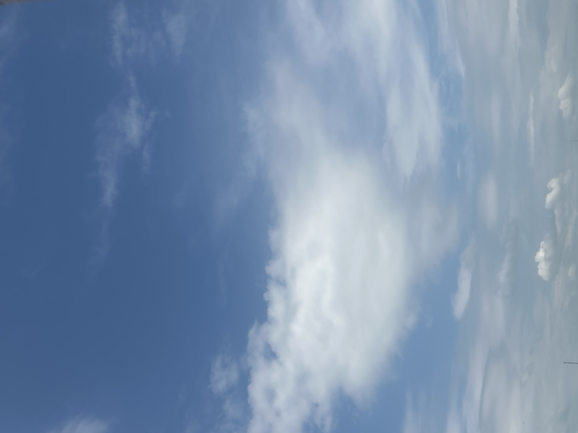 The image shows a daytime sky with a mix of clear blue areas and scattered white clouds. The sky is mostly clear blue on the left side of the image, while the right side is filled with varying cloud formations. The image seems to have been taken outdoors.