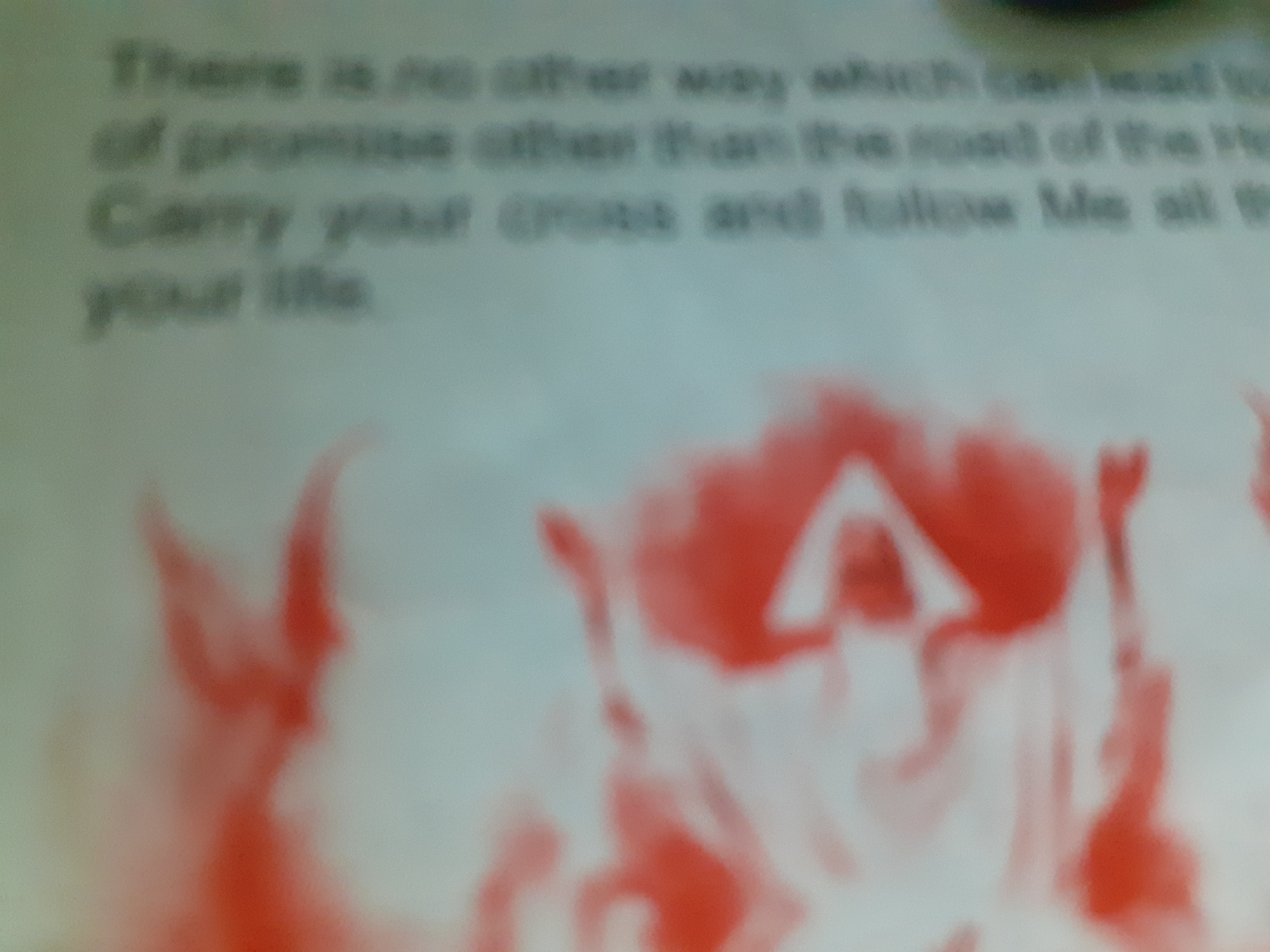 The image shows a blurry, abstract scene with text and a red-and-white graphic. The text, appearing in the upper left quadrant, is difficult to read due to the blurriness and low resolution, but it seems to be a religious quote or passage. Phrases like "There is no other way," "of promise other than," and "Carry your cross and follow Me all th your life" can be faintly discerned. The graphic in the lower portion of the image features abstract shapes in red and white, suggestive of figures or a symbolic representation, possibly religious in nature, given the text. The overall impression is of a document or artwork with a religious theme. There is no discernible information about the location in Jalingo, Nigeria.